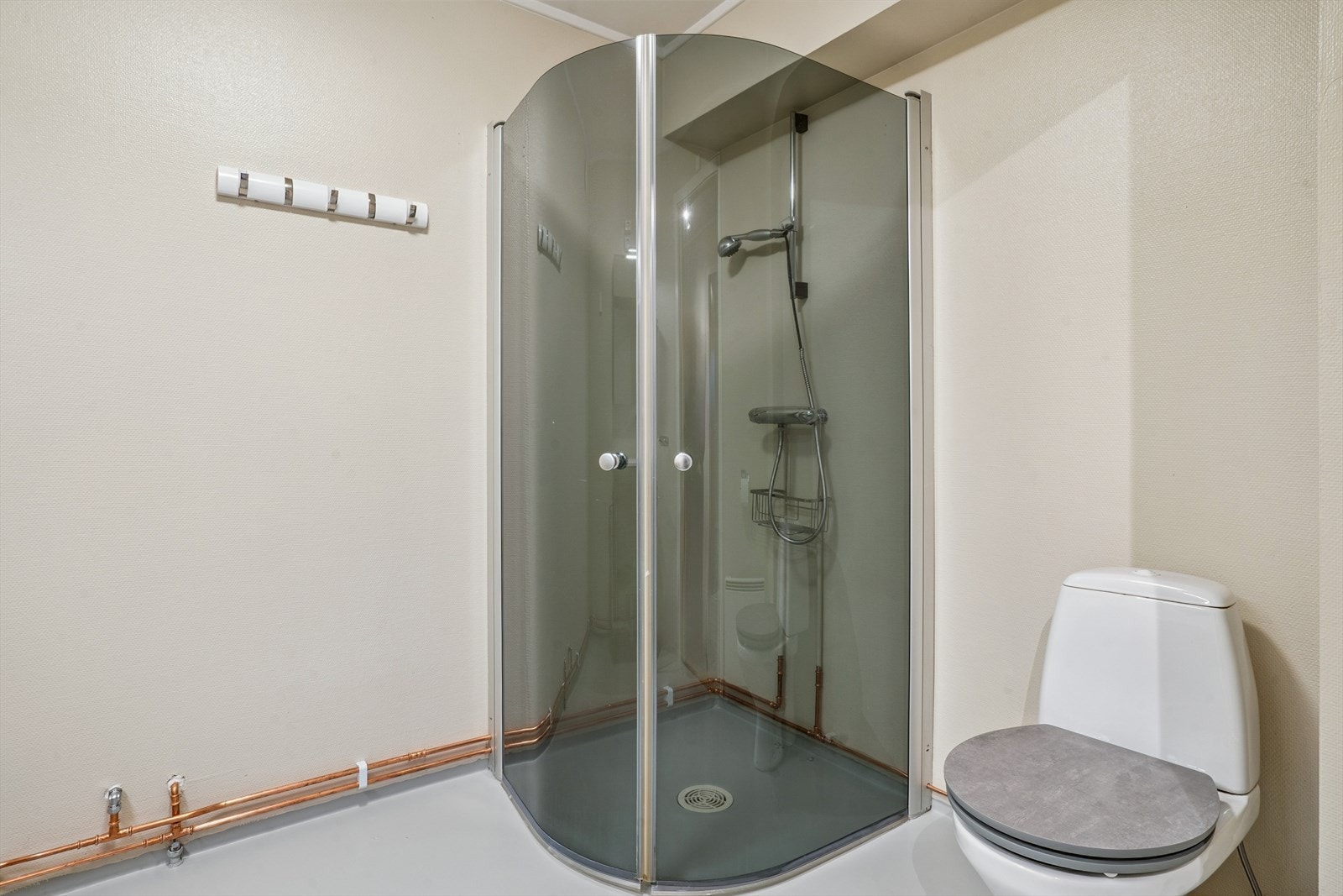 På badet er det dusjhjørne med to glassdører, gulvstående toalett, heldekkende servant i innredning, samt opplegg for vaskemaskin. Galleribilde