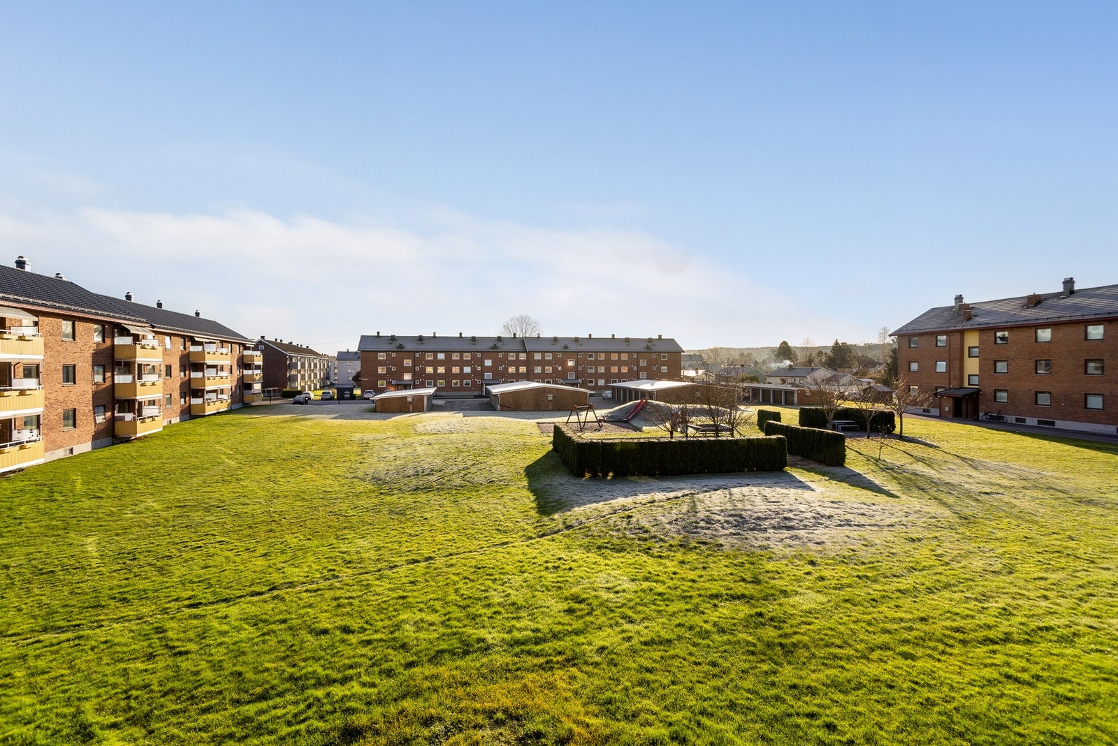 Romslig og fint opparbeidede fellesområder med plen, lekeplass og benker. Asfaltert parkeringsareal og gangvei. Galleribilde