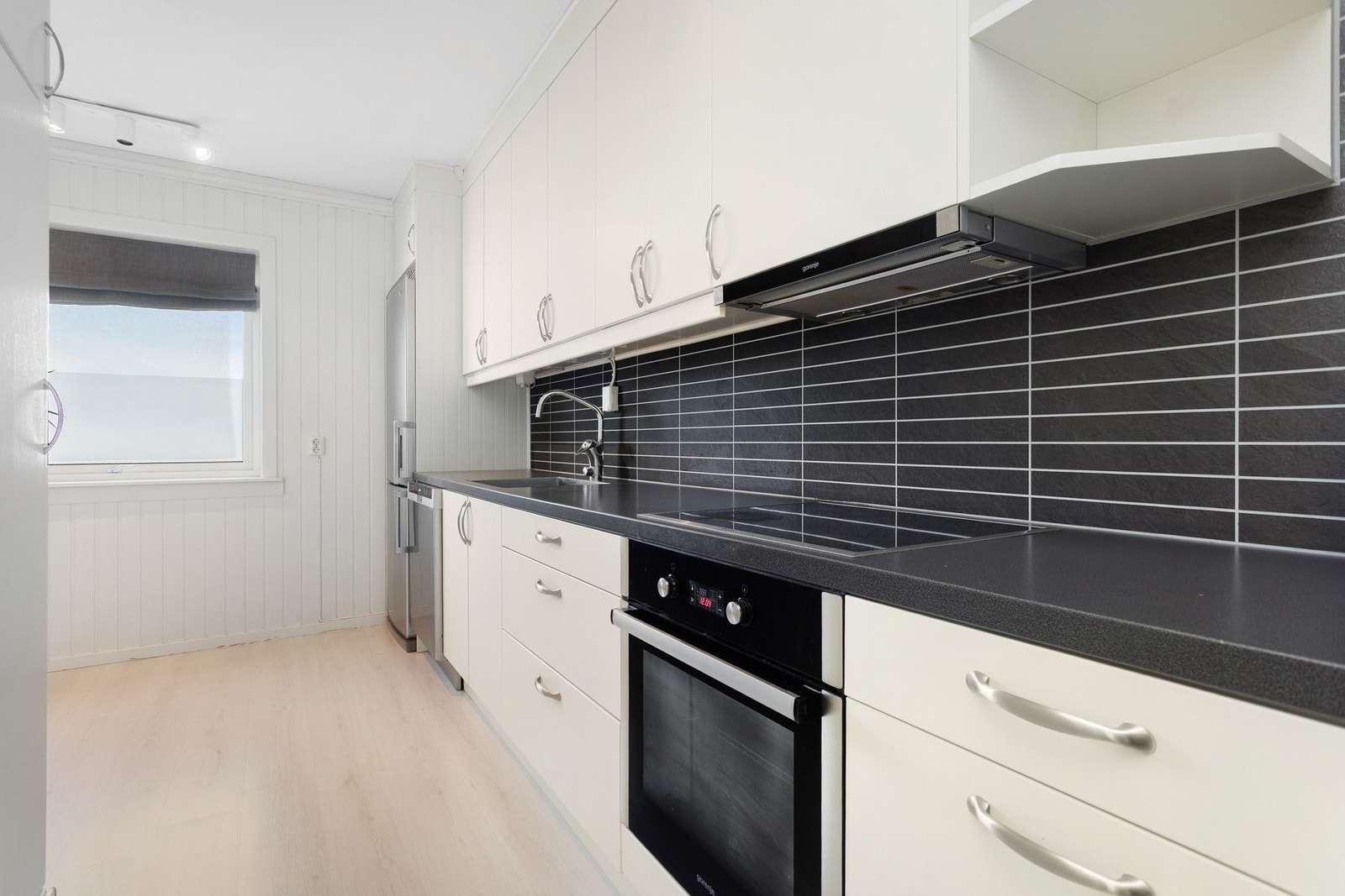 Kjøkkenet har pen innredning med slette fronter, laminat benkeplate og plass for frittstående hvitevarer. Galleribilde