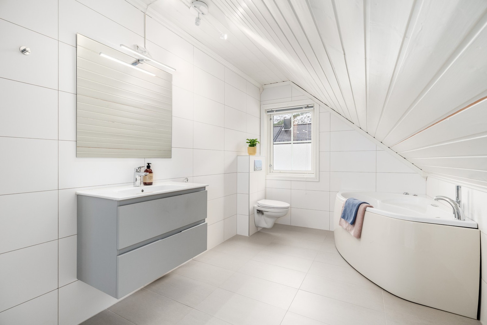 Baderom 2 med vegghengt toalett, moderne baderomsinnredning og badekar. Galleribilde