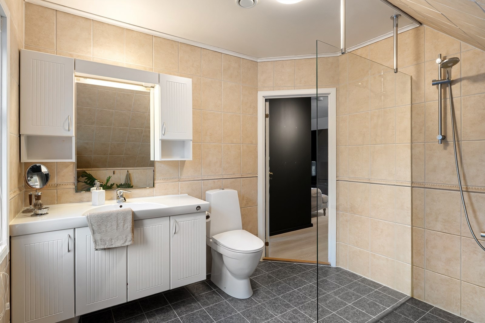 Badet er flislagt og innredet med vask i seksjon, dusj og toalett. Galleribilde