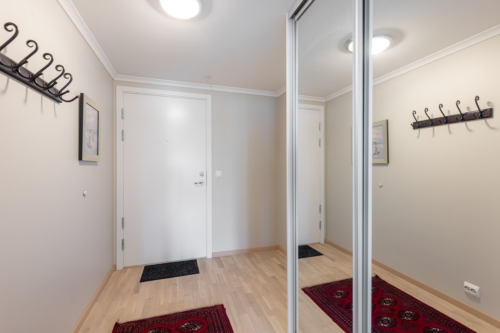 Med adkomst fra felles trappegang kommer man inn i et lyst og romslig gangareal med nydelig parkett på gulvet og lyse veggoverflater. Her er det skyvedørsgarderobe med speildører for sko- og klesoppbevaring. Galleribilde