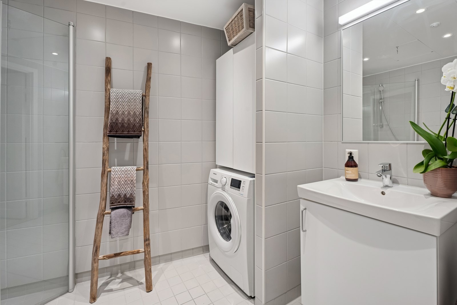 Rommet er utstyrt med servant med underskap, speil med tilhørende belysning, dusjvegger og vegghengt WC. Galleribilde