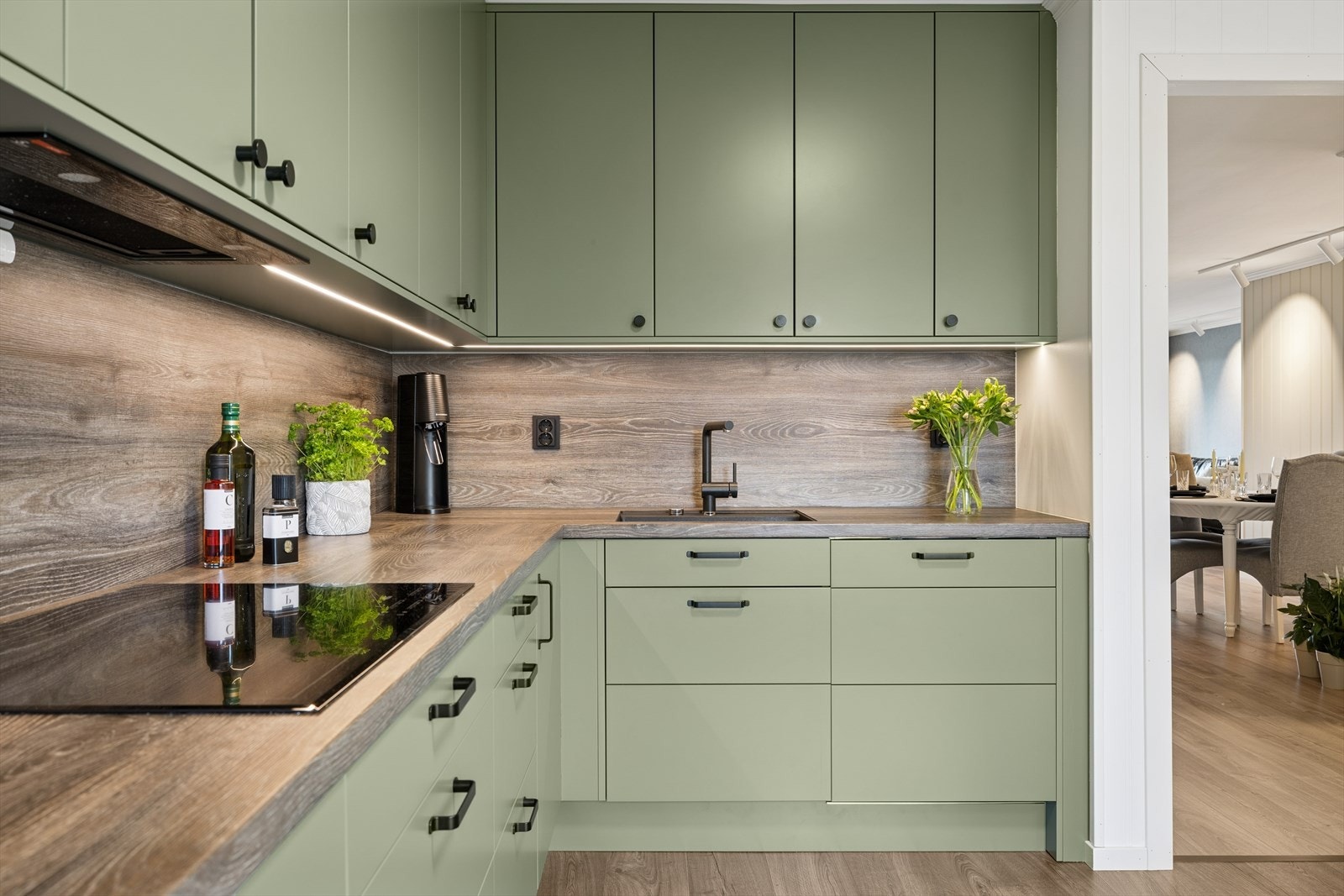 Ny Epoq innredning i 2025 med glatte fronter i en pen grønnfarge og laminat benkeplate. Vegger bak benkeplate har laminatplater, praktisk ved matlaging. Galleribilde