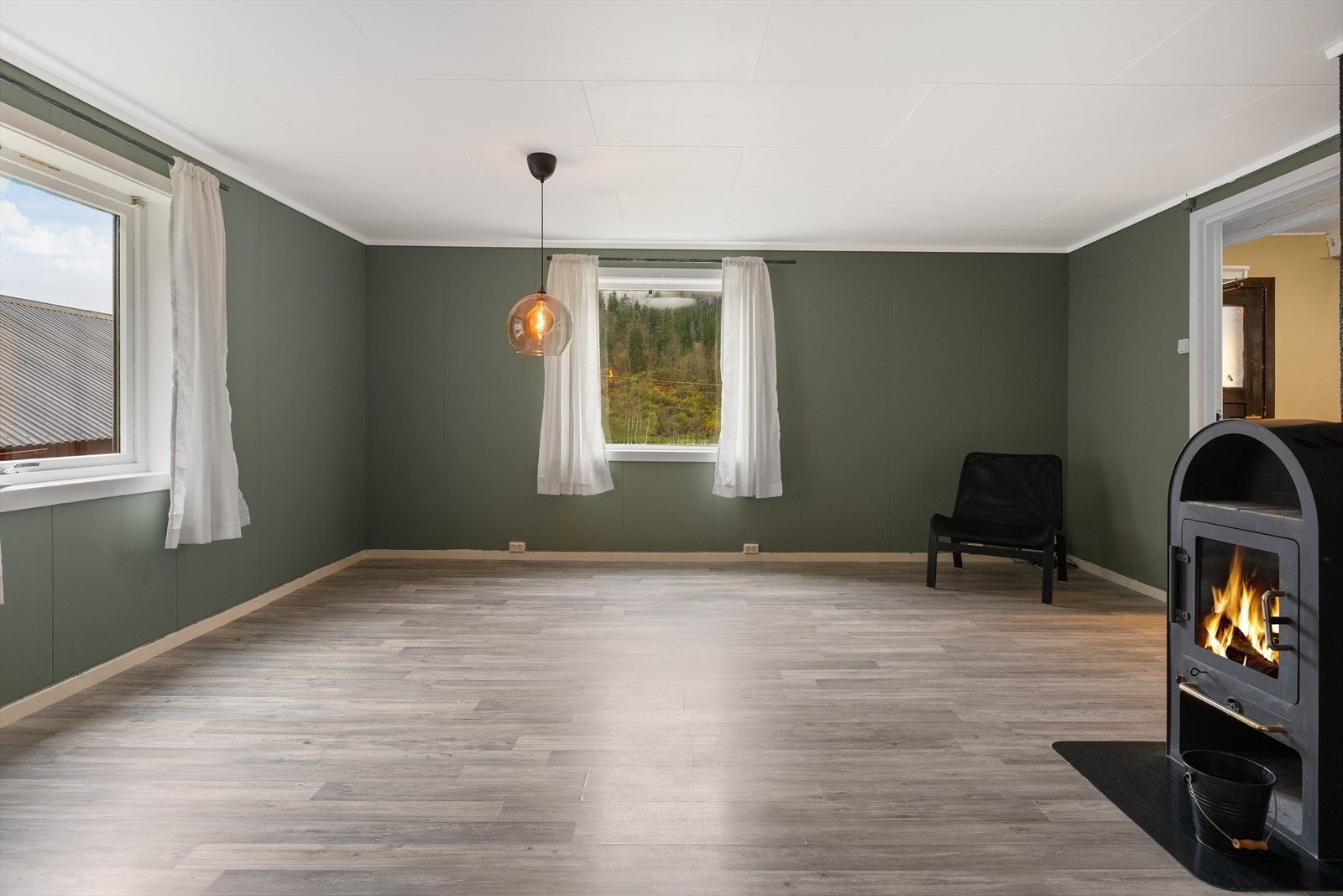 Romslig stue med store vinduer og flott utsikt. Vedovn gir en koselig atmosfære og varme på kalde dager. Galleribilde