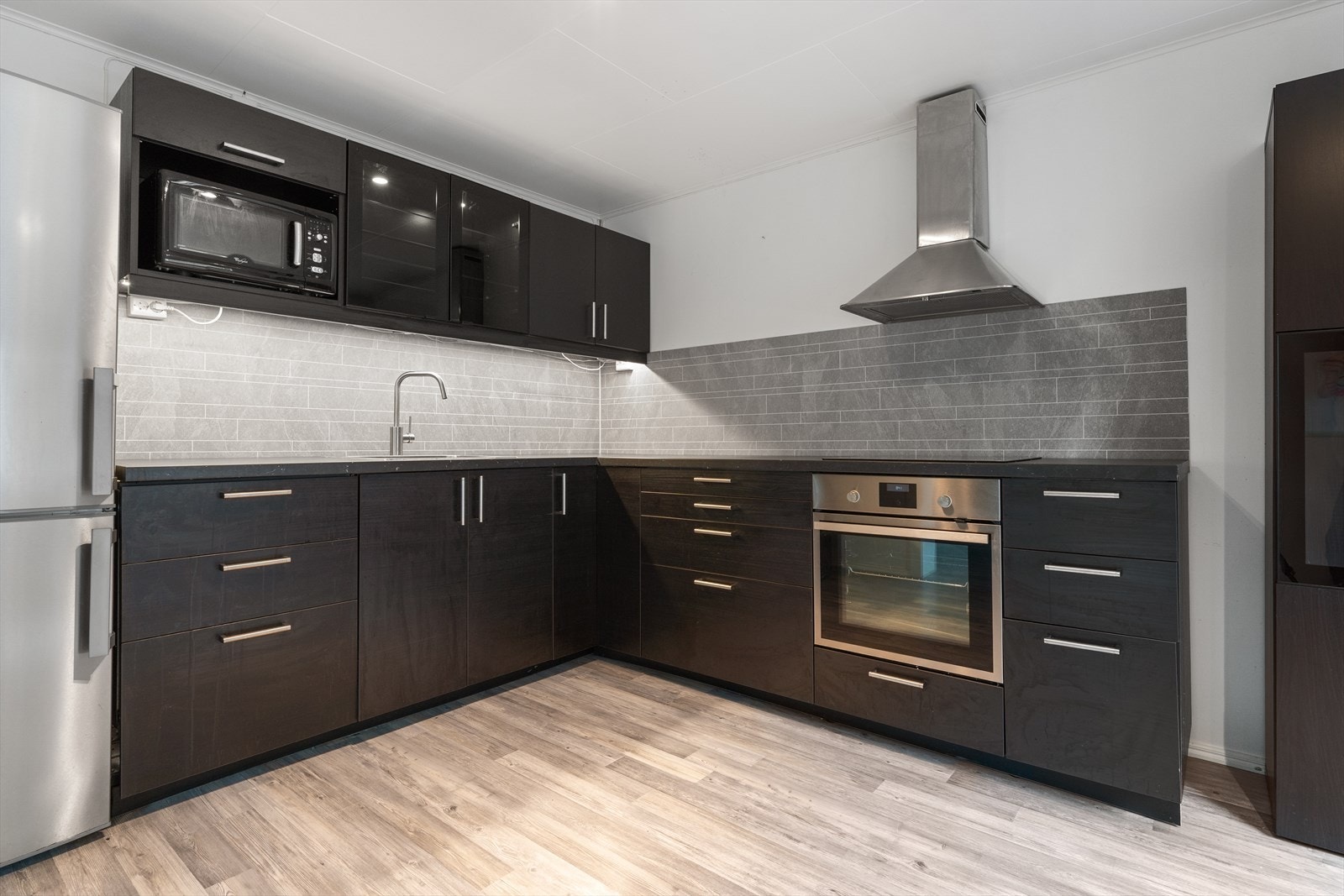 Moderne kjøkken med stilrene skapfronter, integrert komfyr og god benkeplass. Galleribilde