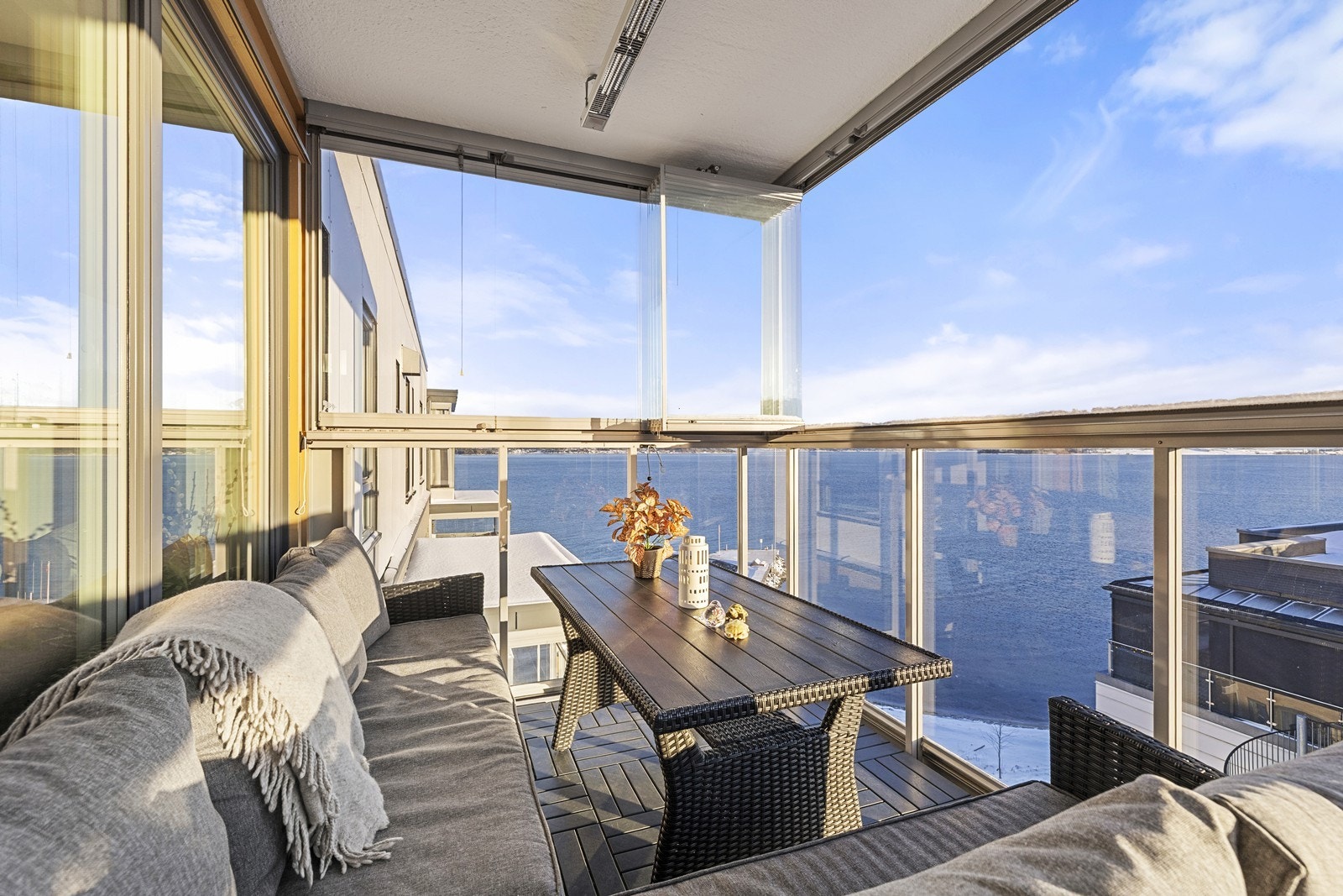 Den innglasserte balkongen utvider stuen og gir en lun uteplass med sjøutsikt, og kan enkelt skyves til side på varme dager. Galleribilde