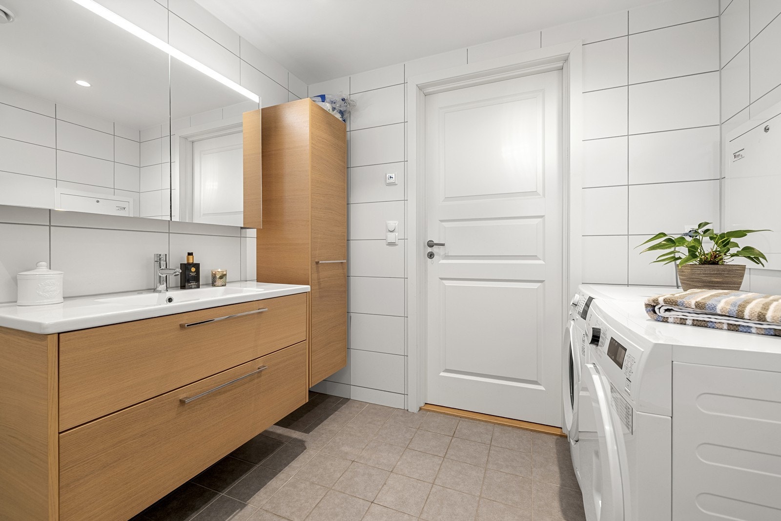 Badet har opplegg for vaskemaskin og tørketrommel, samt ekstra lagring i høyskap. Galleribilde