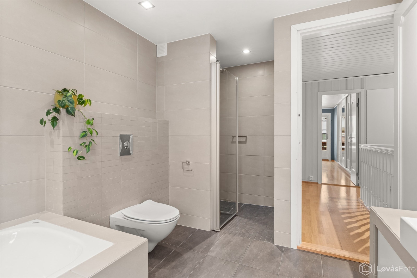 Badet har tidløse fliser i varme bruntoner og vegghengt toalett. Galleribilde