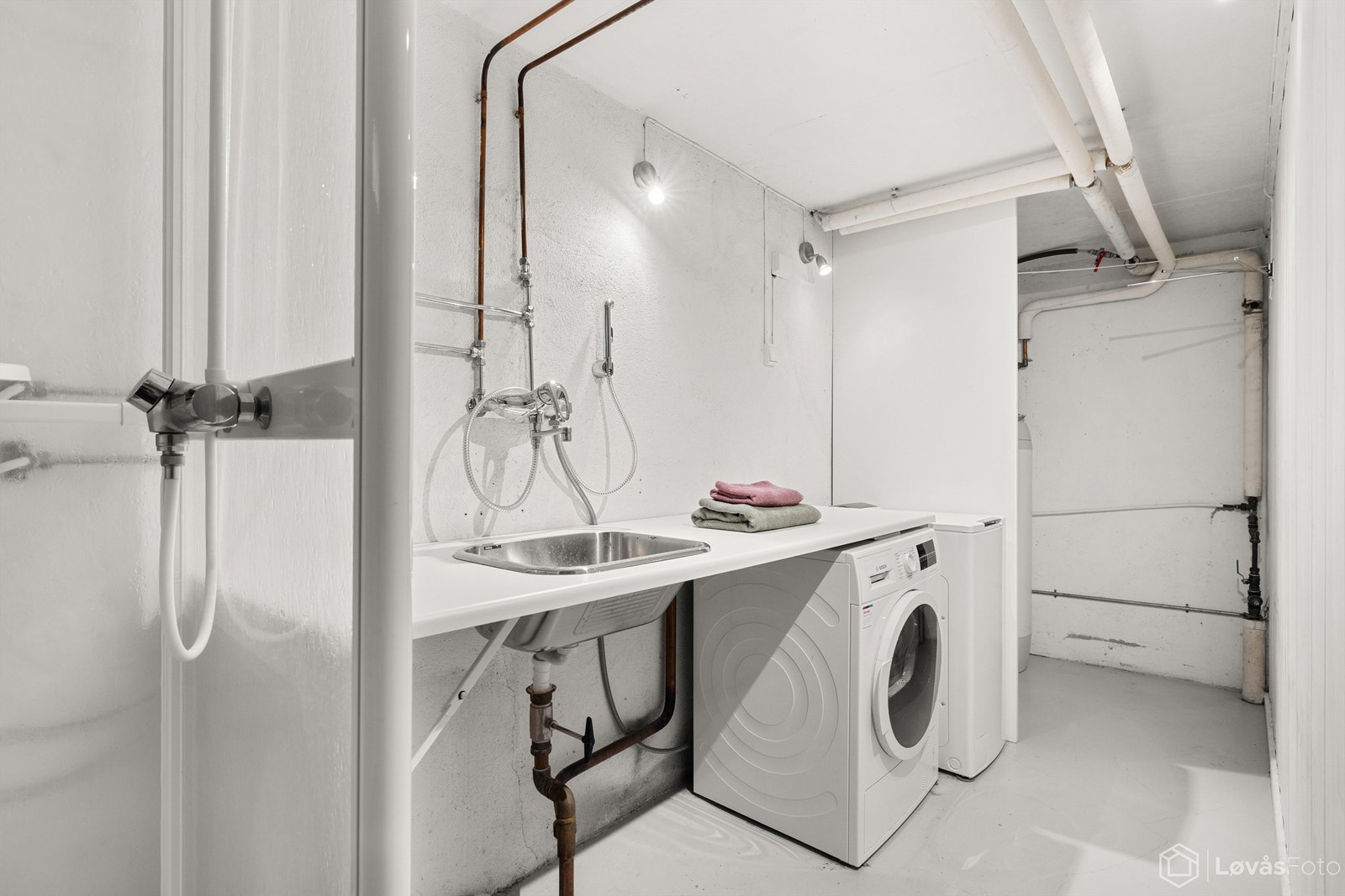 Praktisk vaskerom med opplegg for vaskemaskin, utslagsvask og dusjkabinett. Galleribilde