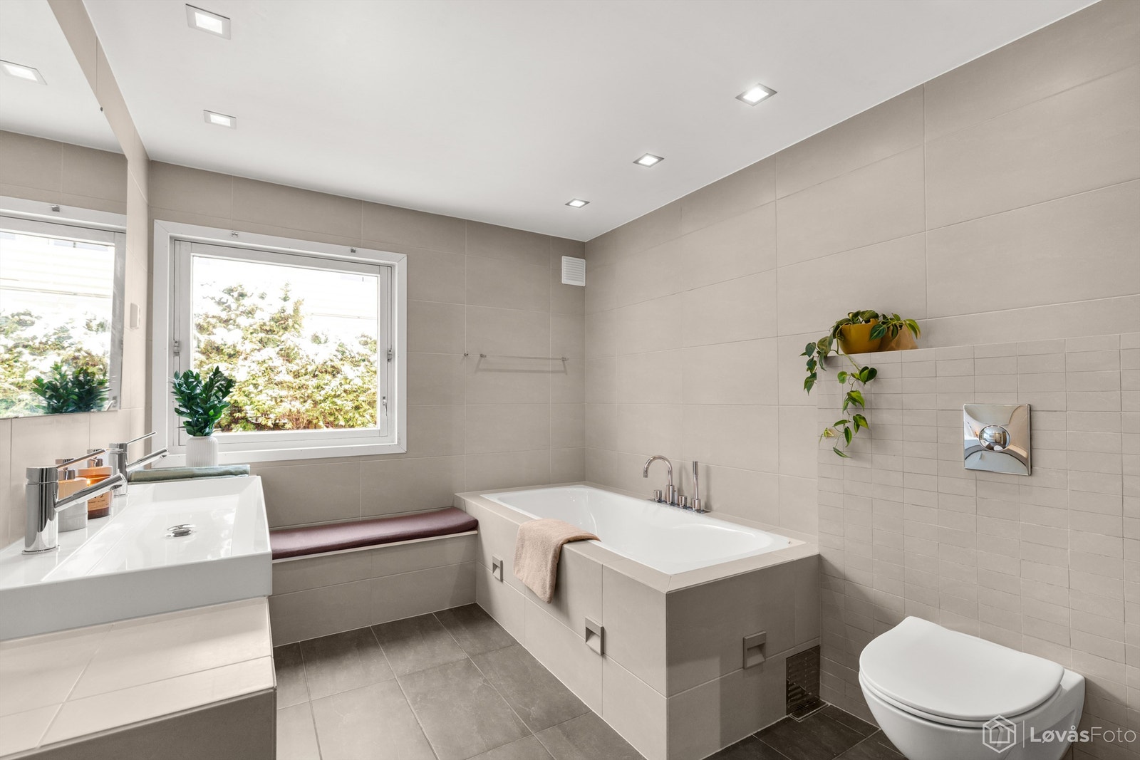 Et stort og delikat baderom med både flislagt badekar og dusjnisje. Galleribilde