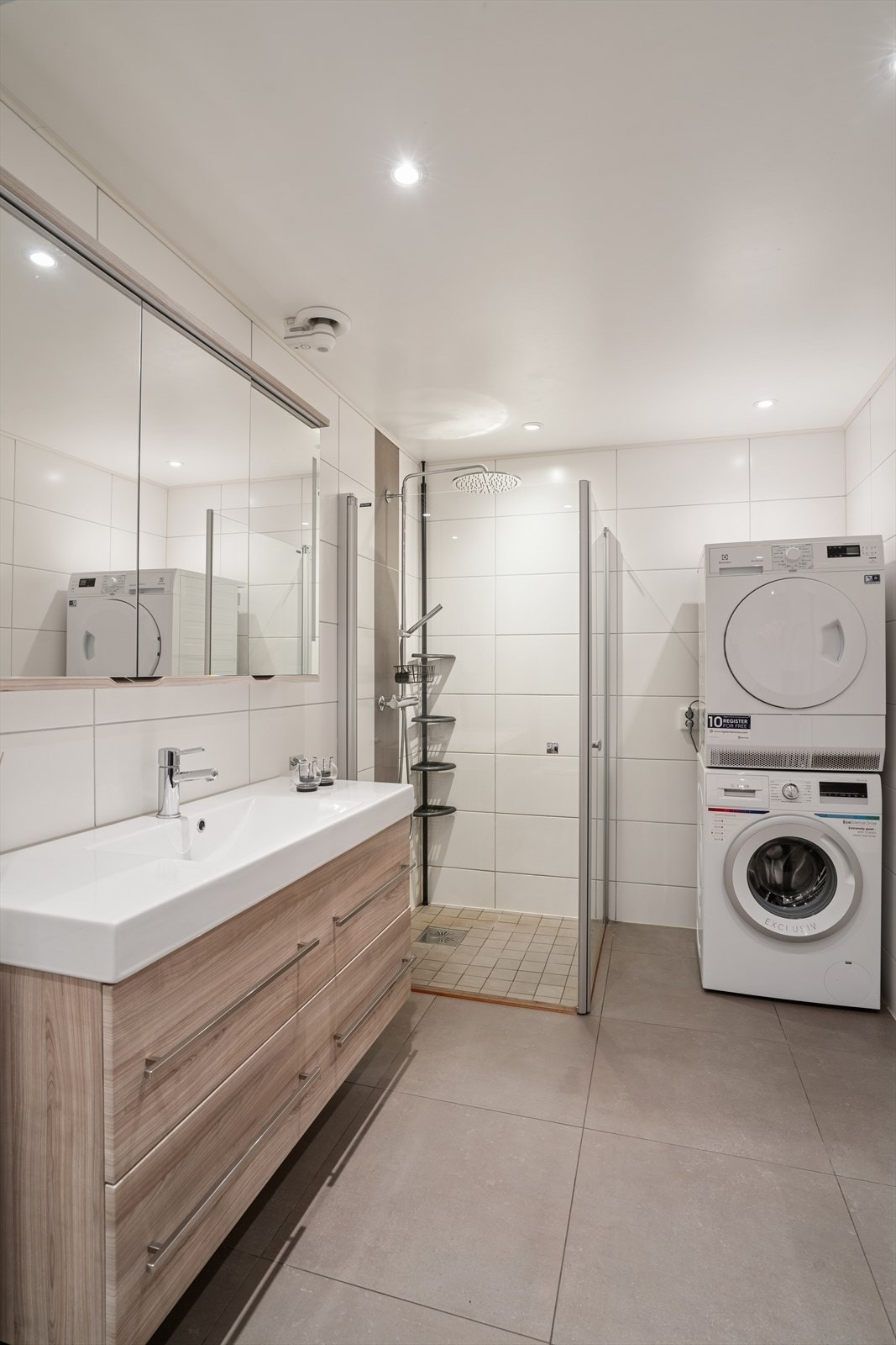 Badet er innredet med servant med underskap, speilskap med lys, vegghengt toalett og dusjhjørne med svingbare glassdører. Det er også opplegg for vaskemaskin. Galleribilde