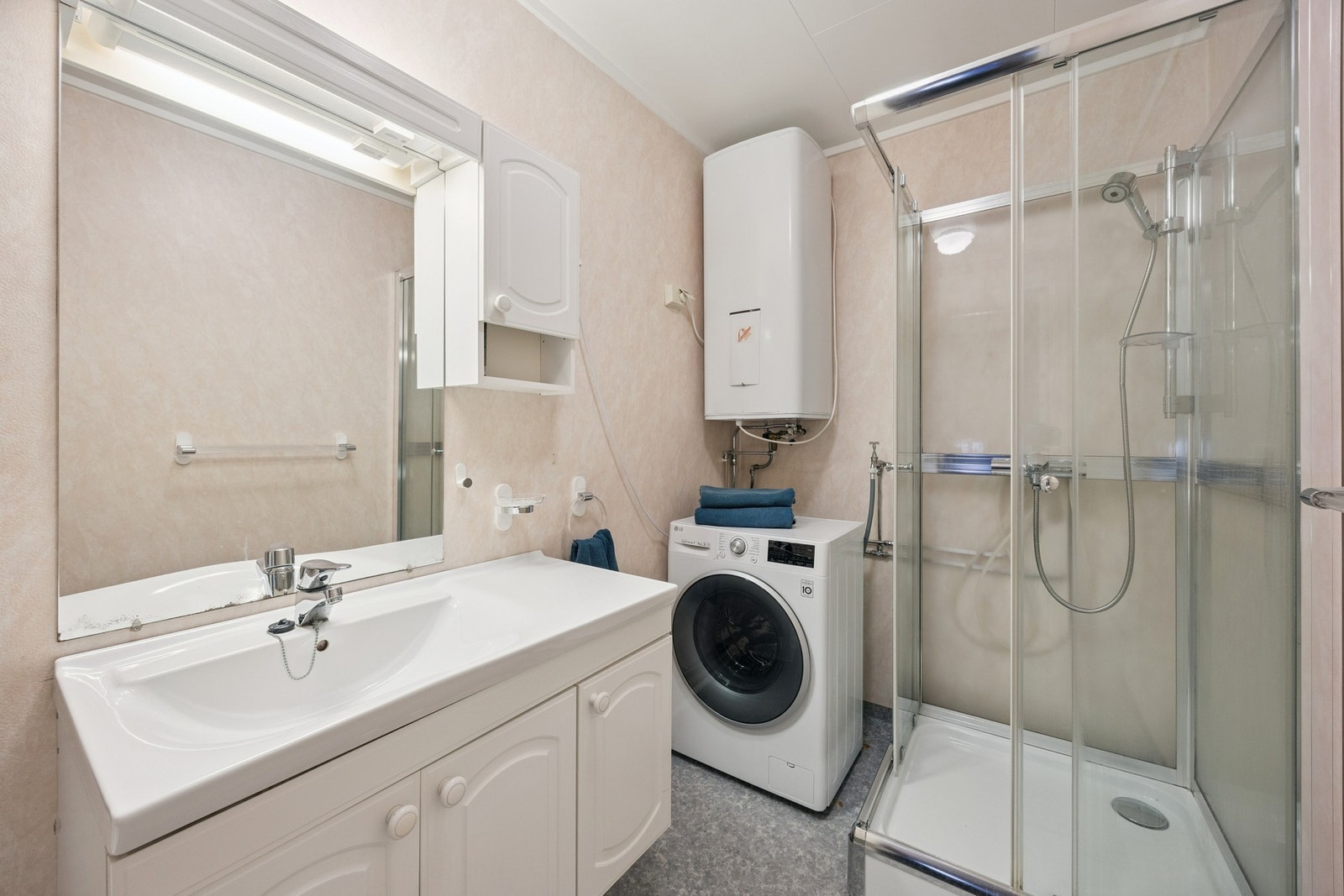 Badet er innredet med servant, dusjkabinett, toalett og opplegg til vaskemaskin Galleribilde