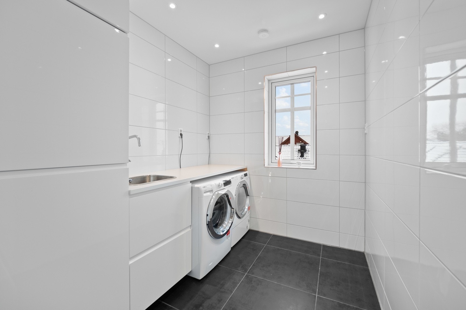 Vaskerommet er helfliset og utstyrt med en hvit innredning, samt nisje til vaskemaskin og tørketrommel. Galleribilde