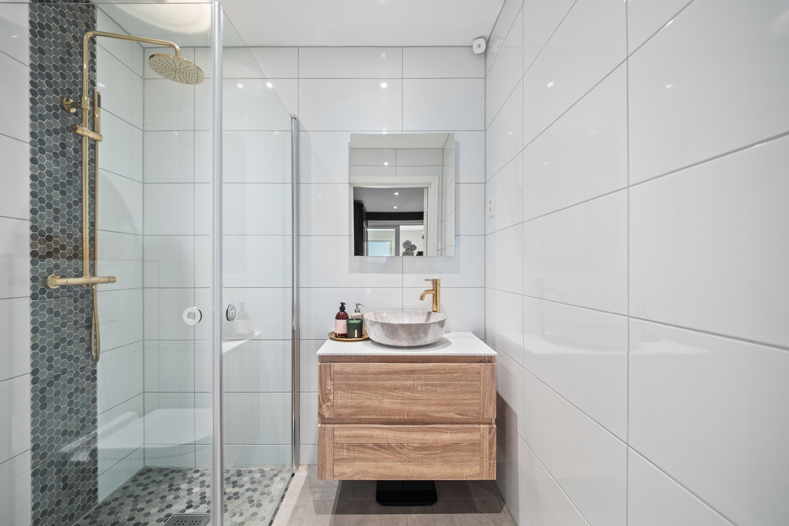 Rommet er helfliset med innslag av heksagonmosaikk i dusjnisjen, samt vannbåren gulvvarme og downlights. Galleribilde