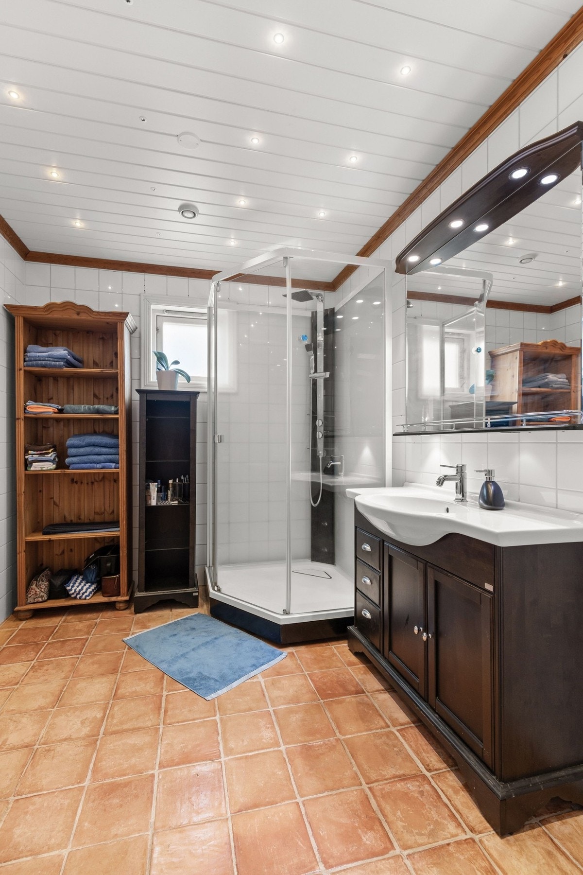 Pent og funksjonelt flislagt bad med fliser med varmekaler i gulv og downlights i himling Galleribilde