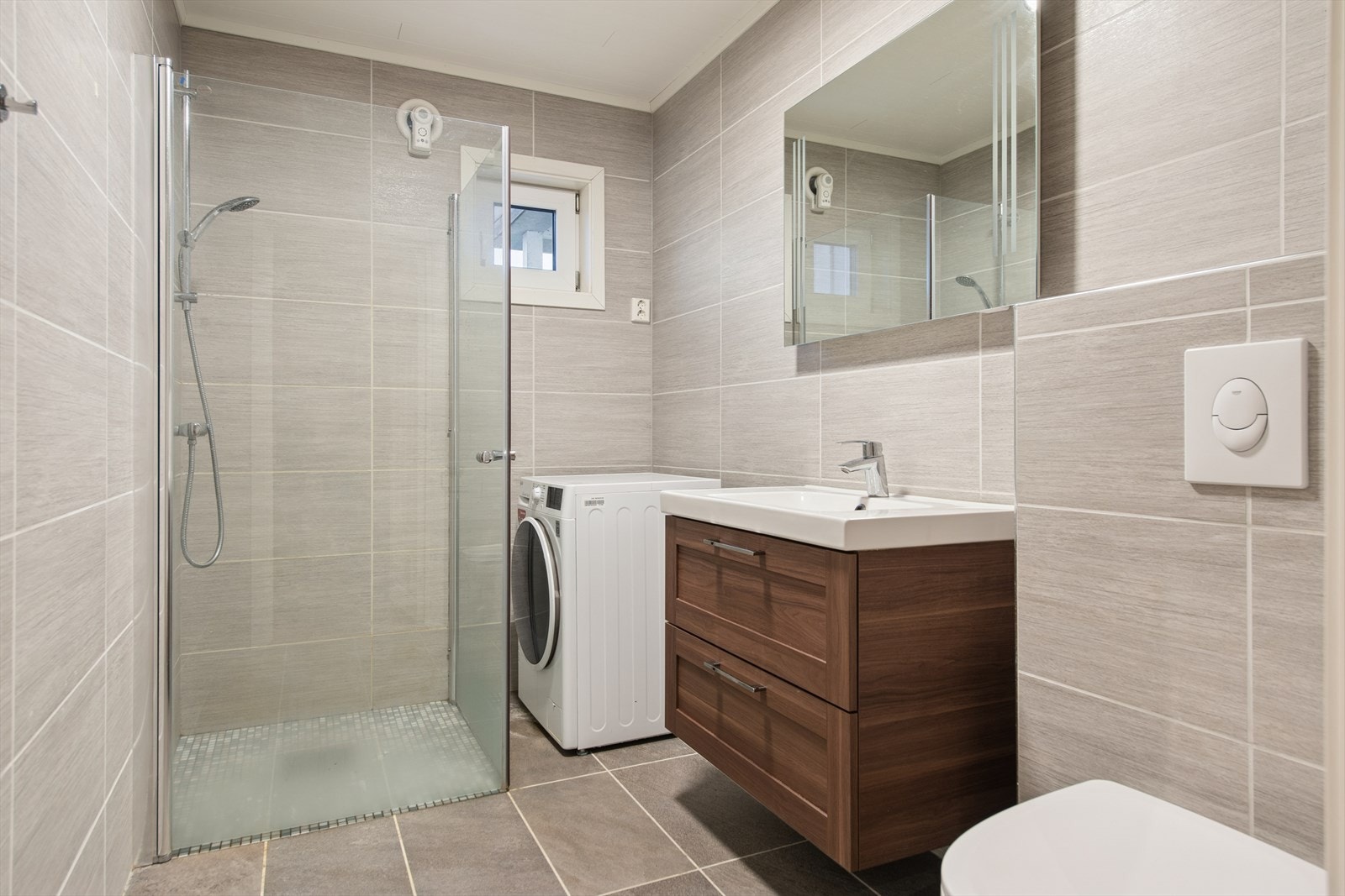 Lekkert baderom fra 2018 med flislagt baderom og gulvvarme, som kombineres med vaskerom. Galleribilde