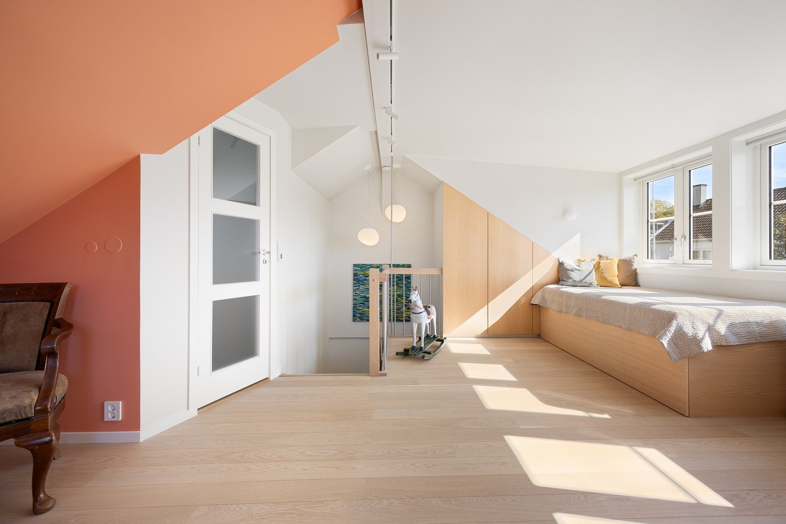 Under en rekke store sprossevinduer er det en stor, plassbygd daybed som kan slås ut til en dobbel gjesteseng. Galleribilde