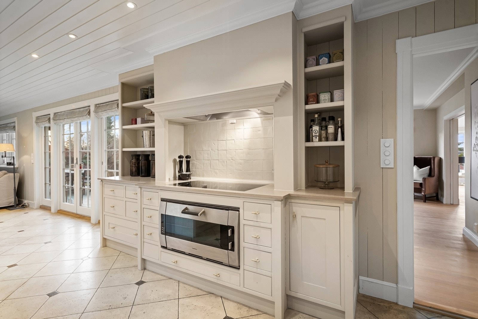 Nylig oppgradert kjøkken (overflater), med malt profilert innredning, avtrekkshette, benkeplate med nedfelt stålkum, stein benkeplate med nedfelt keramisk topp (ny 2025), integrert komfyr, oppvaskmaskin, kjøleskap og frys.