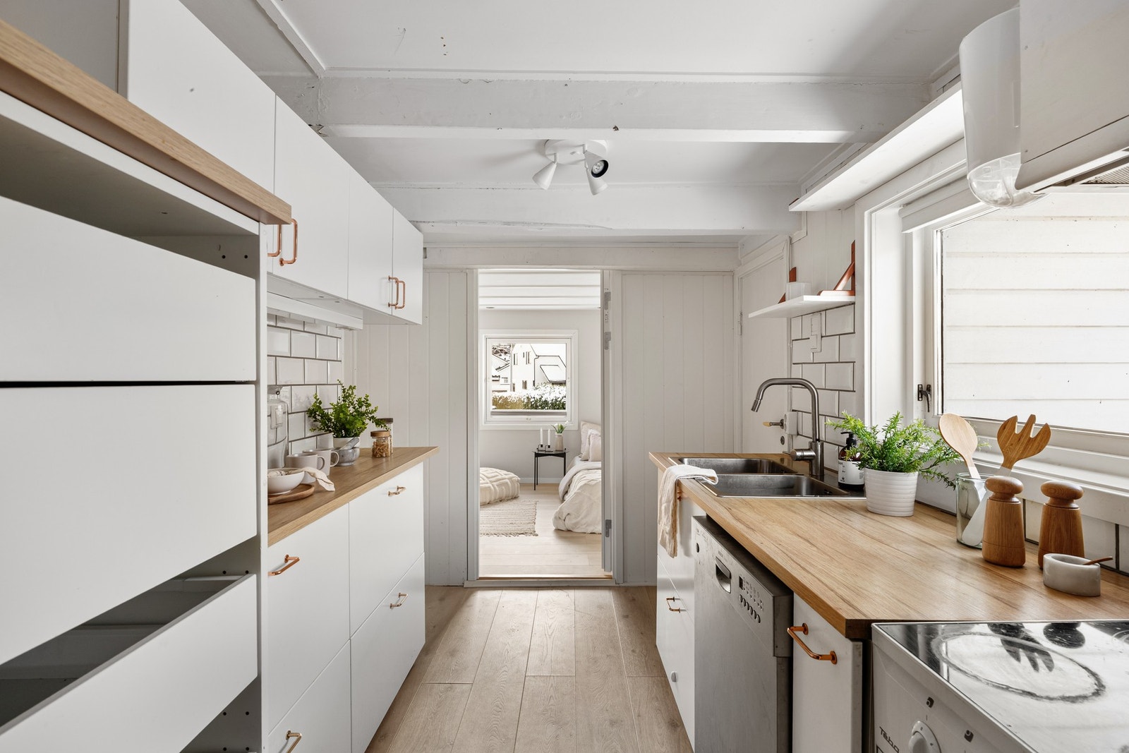 To parallelle seksjoner gir god skapplass, og innredningen har hvite, glatte fronter, dobbel oppvaskkum og benkeplate av laminat Galleribilde