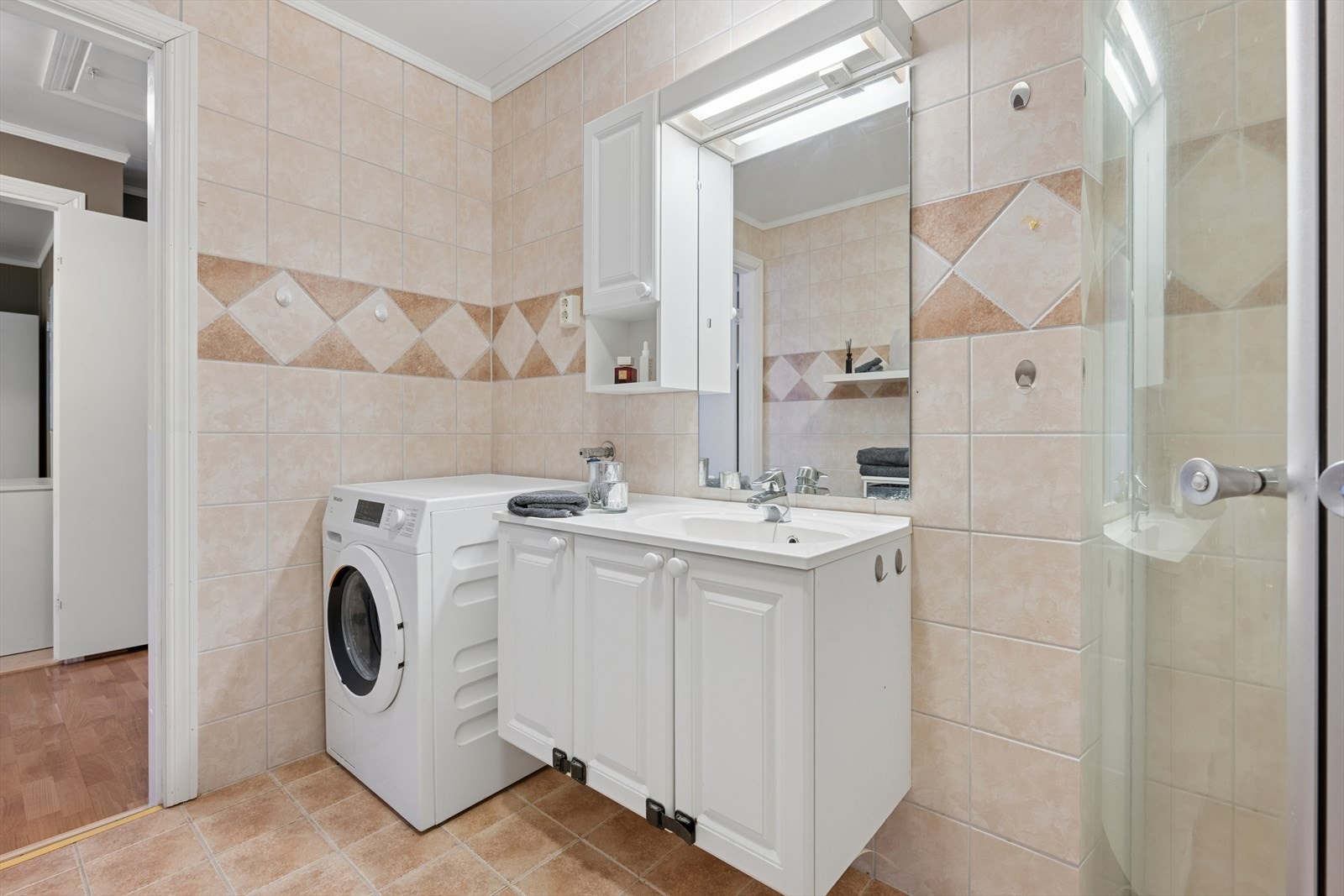 Pent bad med fliser på vegger og gulv, samt varmekabler i gulv. Rommet er innredet med heldekkende servant nedfelt i romslig benkeskap, overskap og belyst speil. Galleribilde