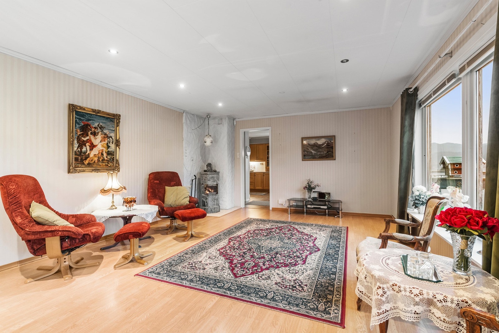 Romslig stue med lyse overflater og vedovn. Galleribilde