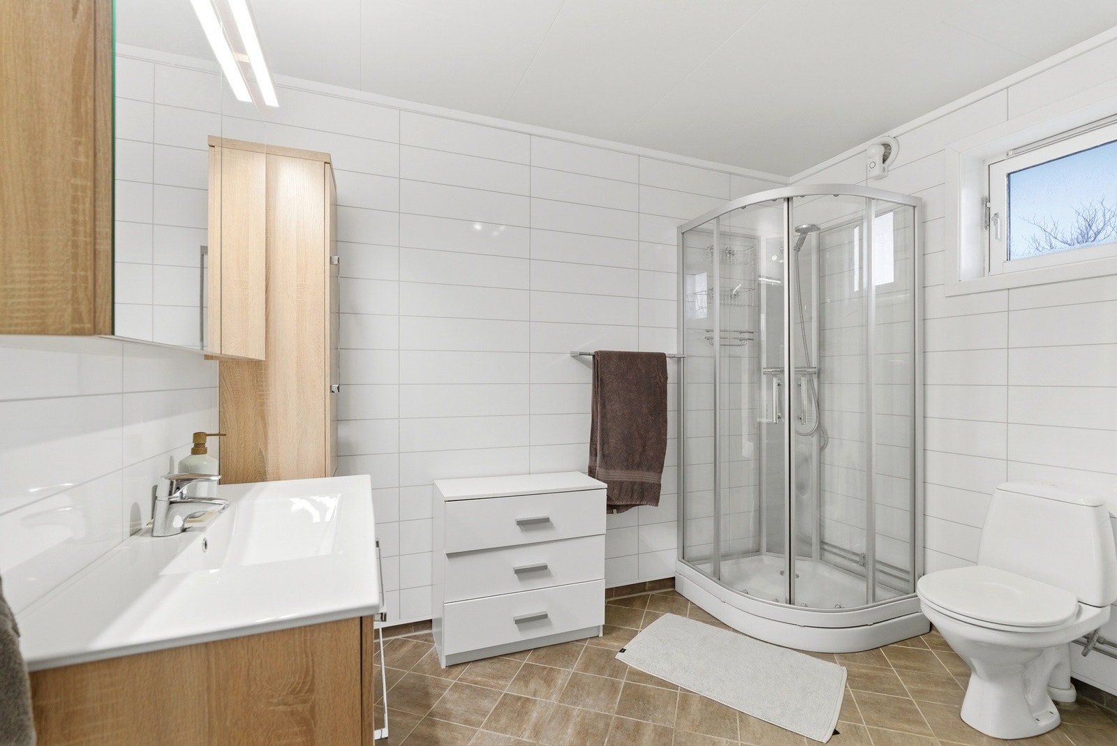 Lyst og romslig bad som er modernisert i 2015 - Baderomsplater på veggene og flislagt gulv med varmekabler. Galleribilde