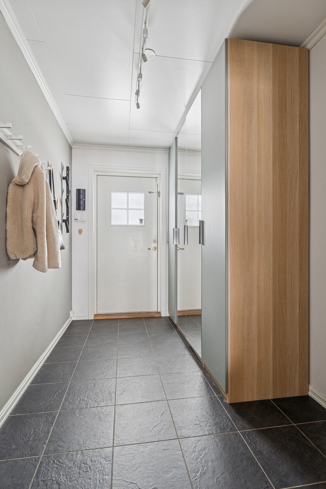 Praktisk entré med flislagt gulv med gulvvarme og plass til garderobeskap. Galleribilde
