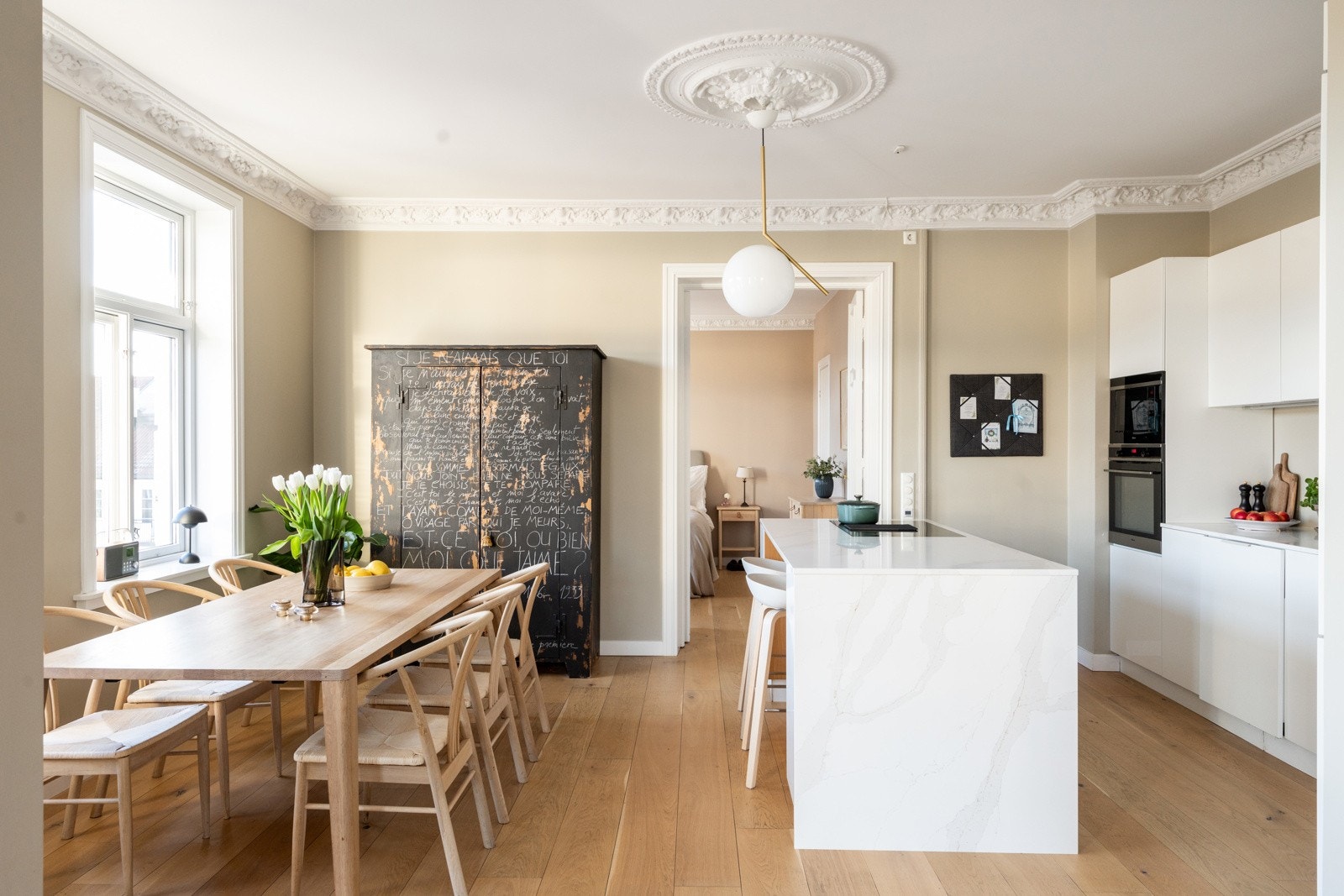 Kvik Senti kjøkken fra 2021. Kjøkkenet har en åpen og funksjonell løsning med slette fronter og Calacatta Goldlight benkeplate av stein. Galleribilde