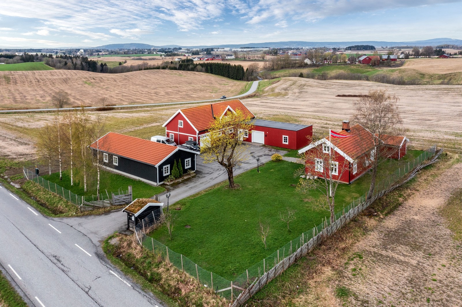 Fin hage opparbeidet med plen og beplanting, samt asfaltert innkjøring og gårdsplass. Galleribilde