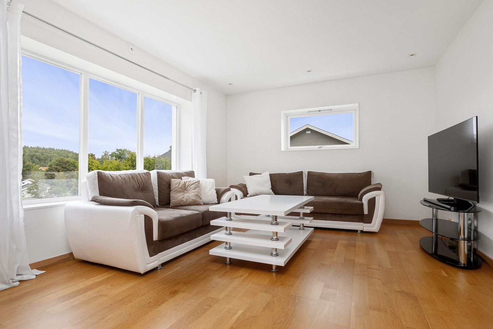 Lys stue med plass til sofaløsning med tilhørende møblementer og tv-seksjon Galleribilde