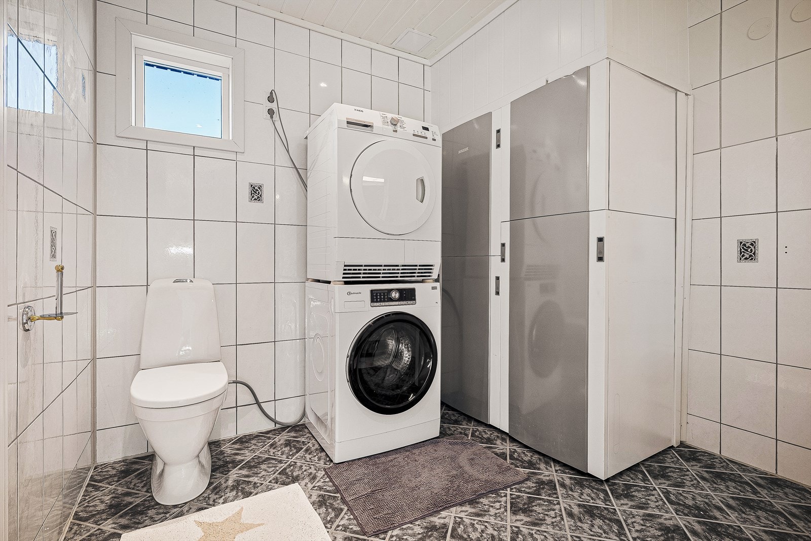 Videre kommer du inn på badet i 1.etg som pr. idag også benyttes som et tekniskrom. Her er det opplegg for varmepumpe og opplegg for vaskemaskin og tørketrommel Galleribilde