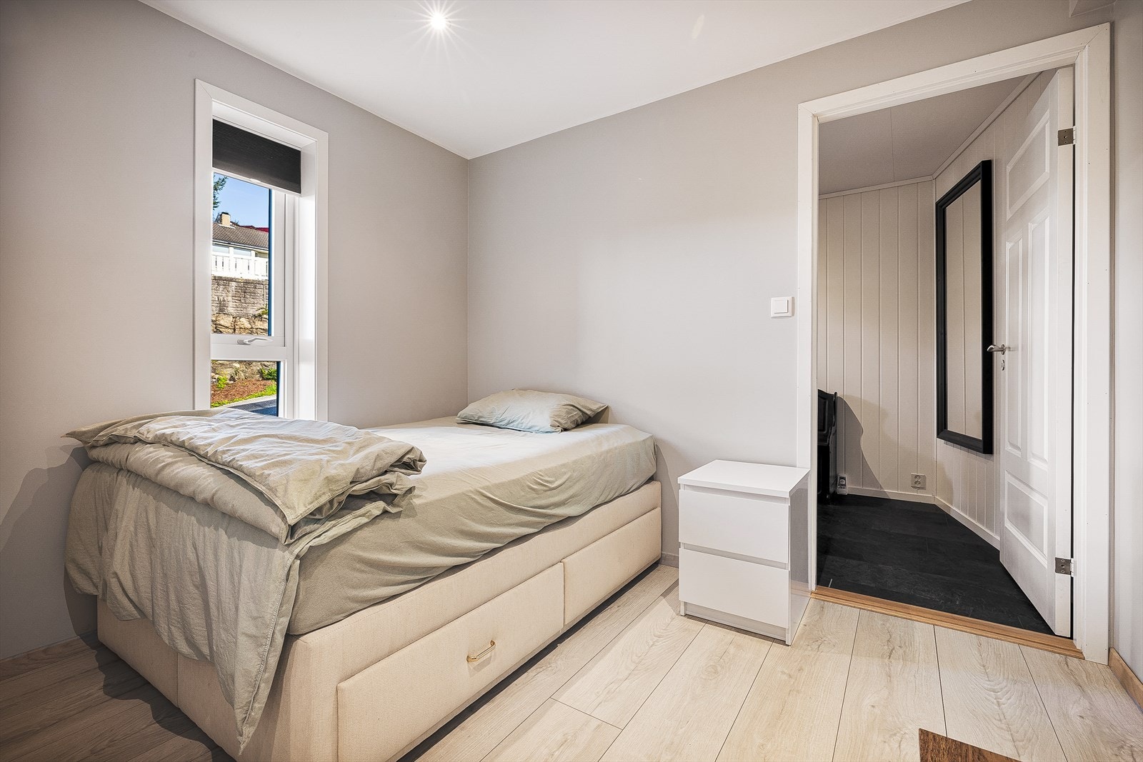 I den åpne stue/kjøkkenløsningen er det plass til både sofa og en soveløsning. Her er det laminat på gulv, malt platekledning på vegger og i himling med innfelte spotlights. Galleribilde