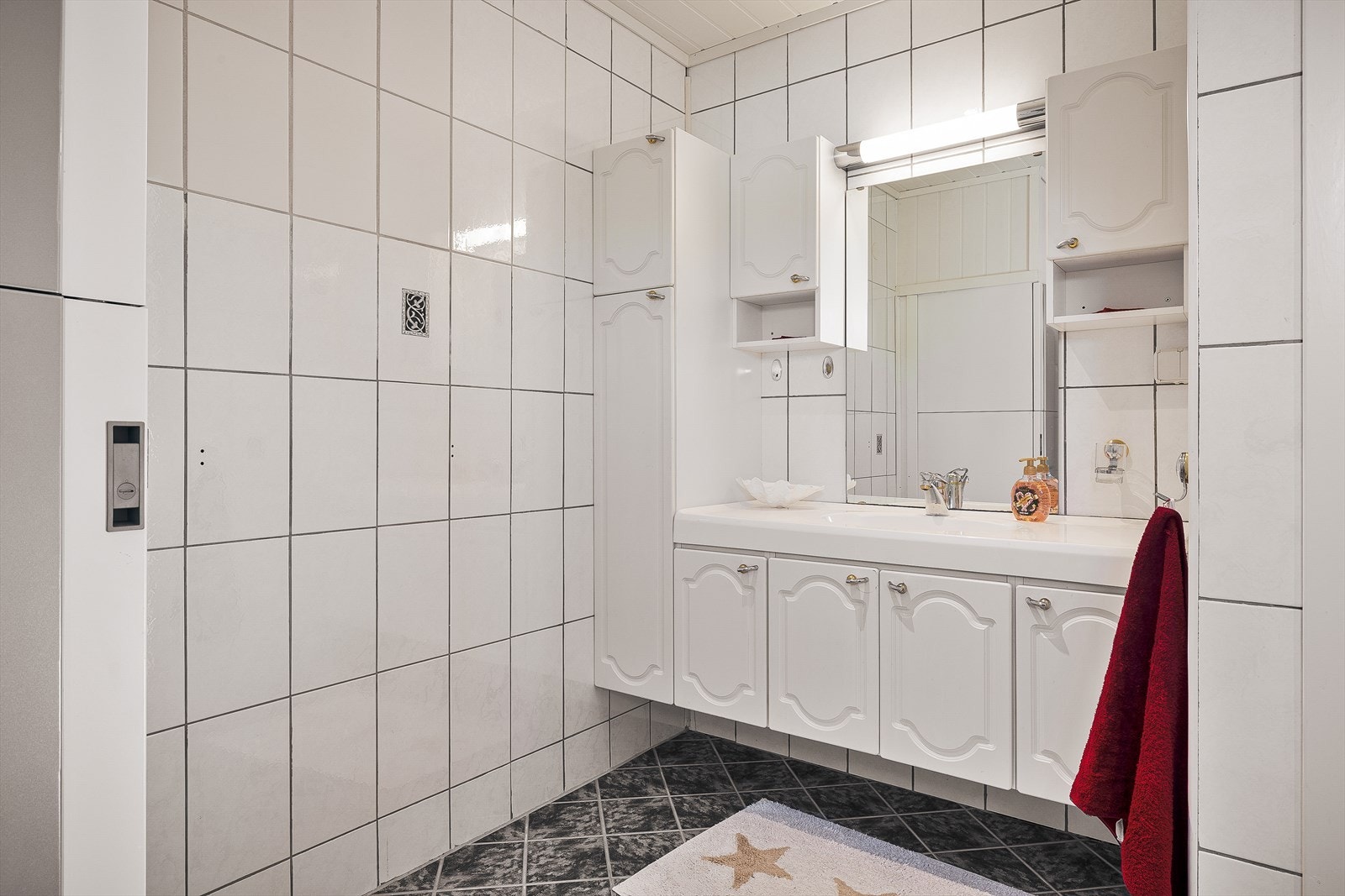 Badet/teknisk rom måles til 7,5m² og består av keramiske fliser på gulv og vegger med smartpanel i himling. Her får du servantløsning med møblement og speil, belysning og toalett. Galleribilde