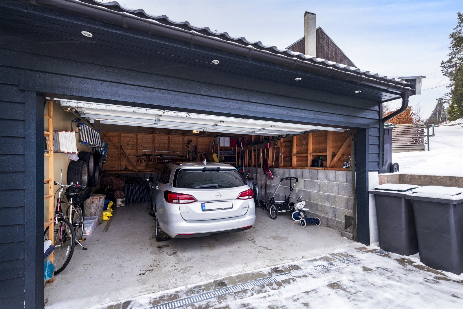 Garasje for en bil med fjernstyrt leddport. Garasjen er romslig med god plass til dekk og sykler Galleribilde