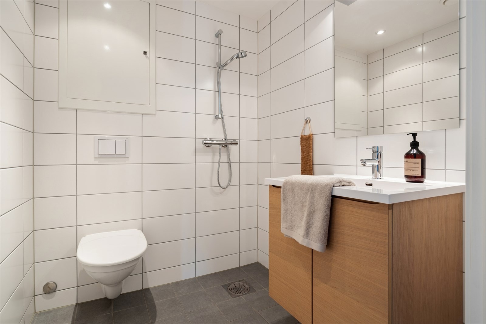 Badet er fra 2016 og er helfliset med fliser på gulv og vegger, og et malt tak med downlights. Rommet er utstyrt med et vegghengt toalett med innebygd sisterne, en servantinnredning med speil, og en dusj. Galleribilde