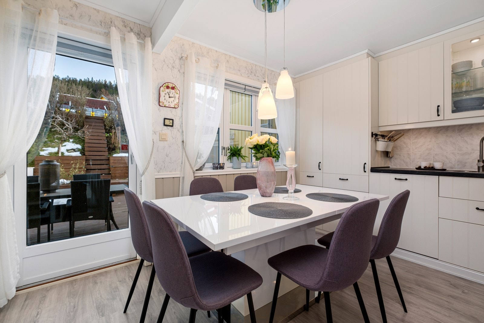 Kjøkken med store vindusflater som gir rikelig lys og plass til et stort spisebord - perfekt for sosiale måltider Galleribilde