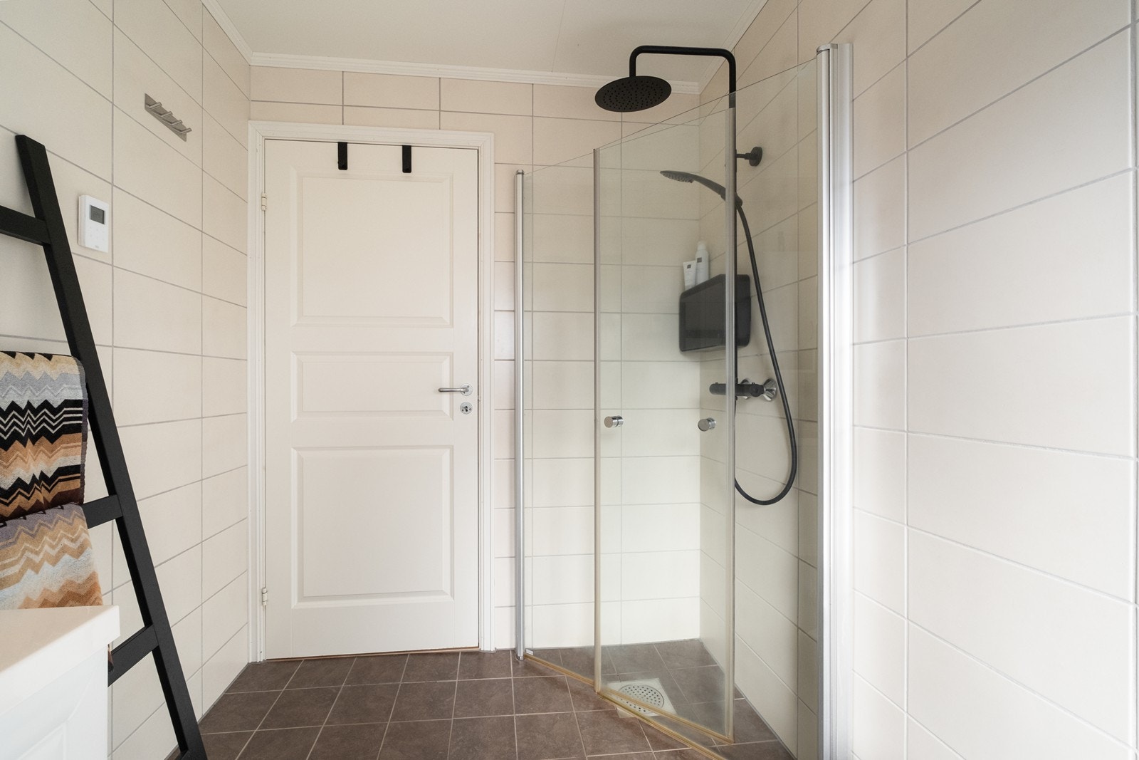 I hjørnet er det montert dusj med innfoldbare glassvegger, som gir en effektiv utnyttelse av rommet. Galleribilde