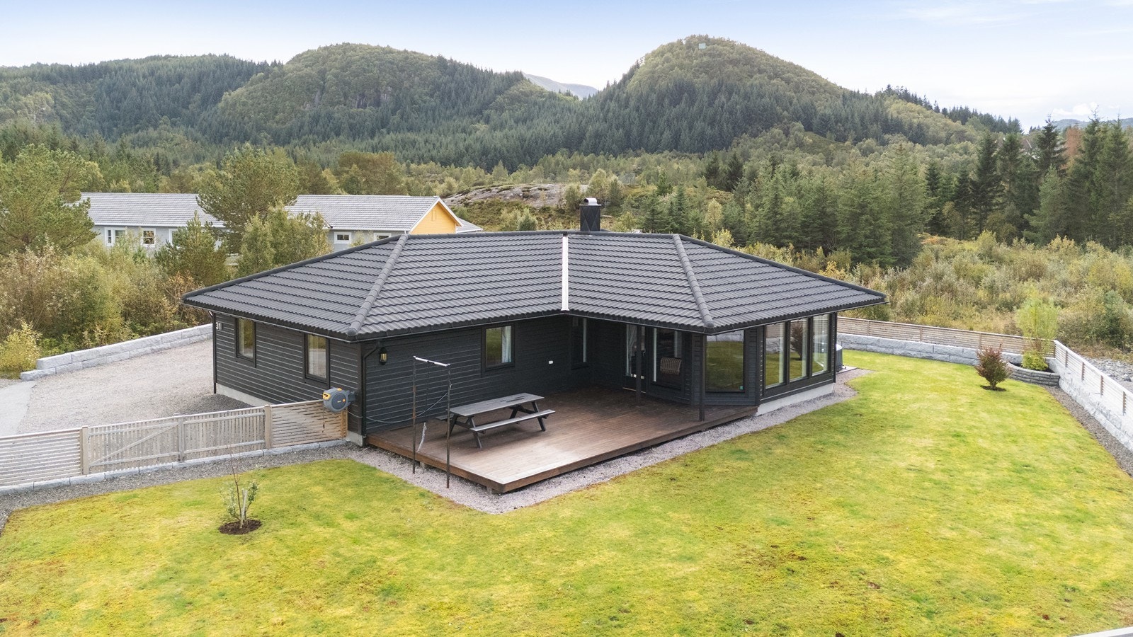 Boligen har en terrasse av treverk og en velholdt, inngjerdet hage. Galleribilde