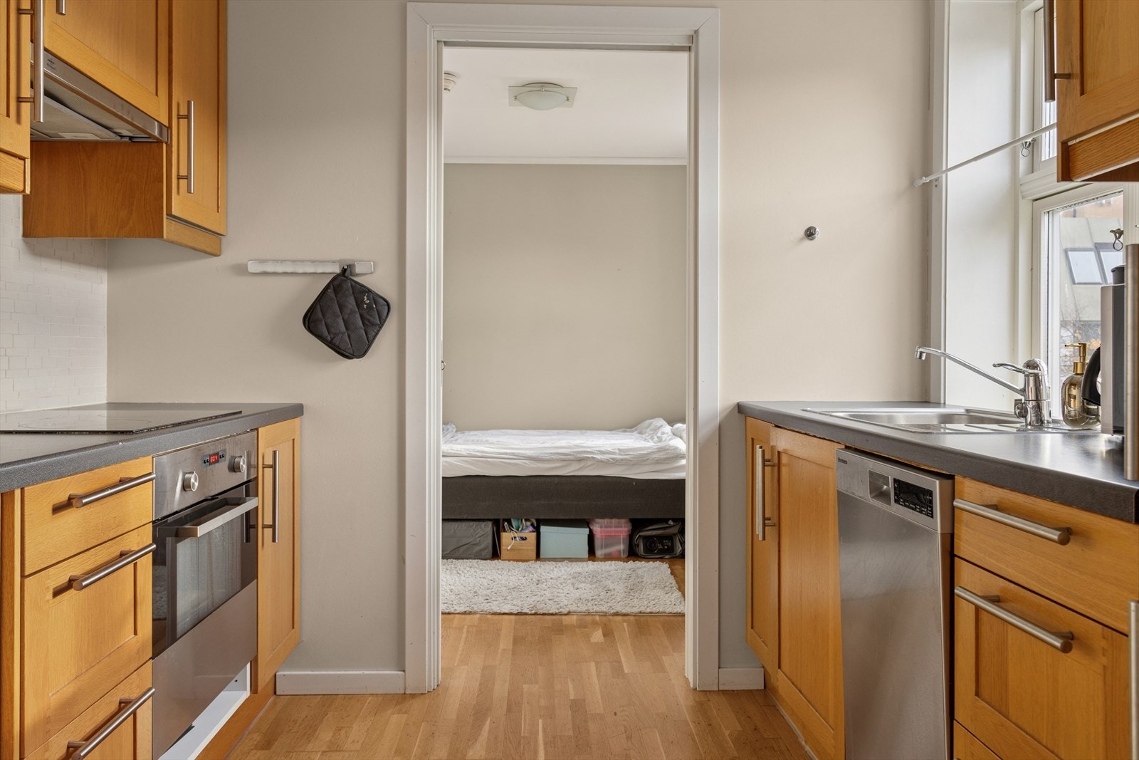 Kjøkkenet har parkettgulv, og malt overflate og flis på vegg over benkeplate på vegger. Malt overflate i himling. Innredning med mekanisk avtrekksvifte over stekesonen og opplegg for vaskemaskin. Det er integrert stekovn og platetopp. Galleribilde