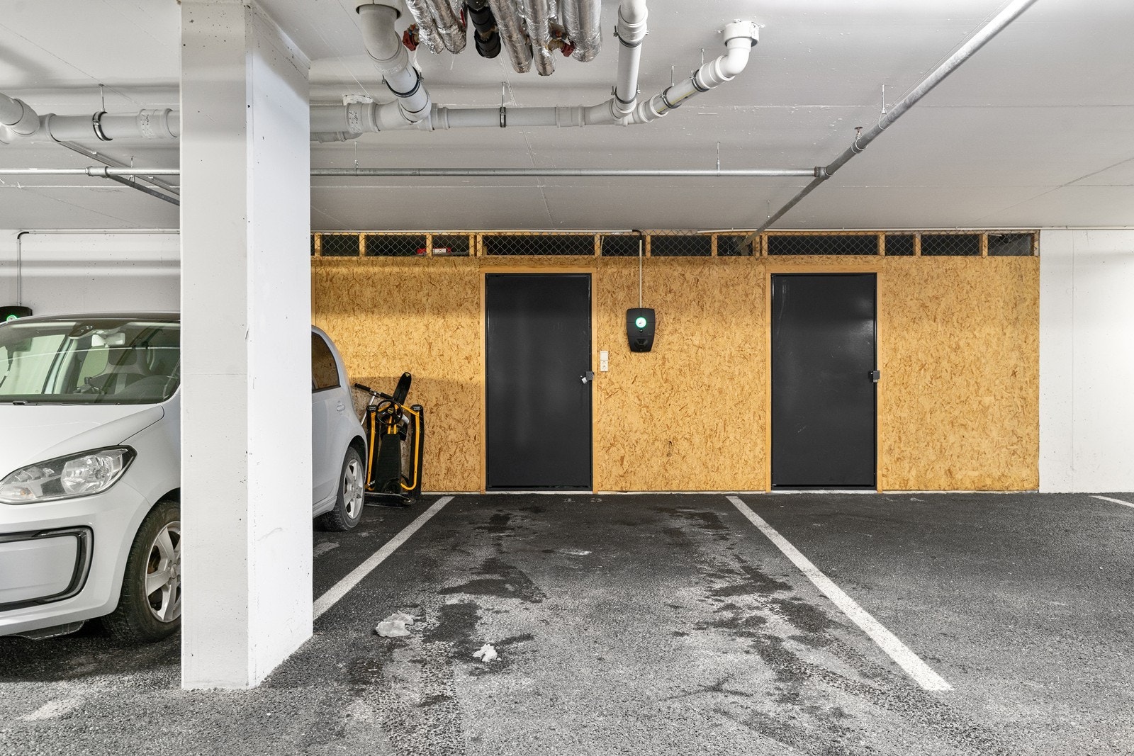 Parkeringsplass med el. bil lader. Bod i forlengelsen av parkeringsplassen. Galleribilde