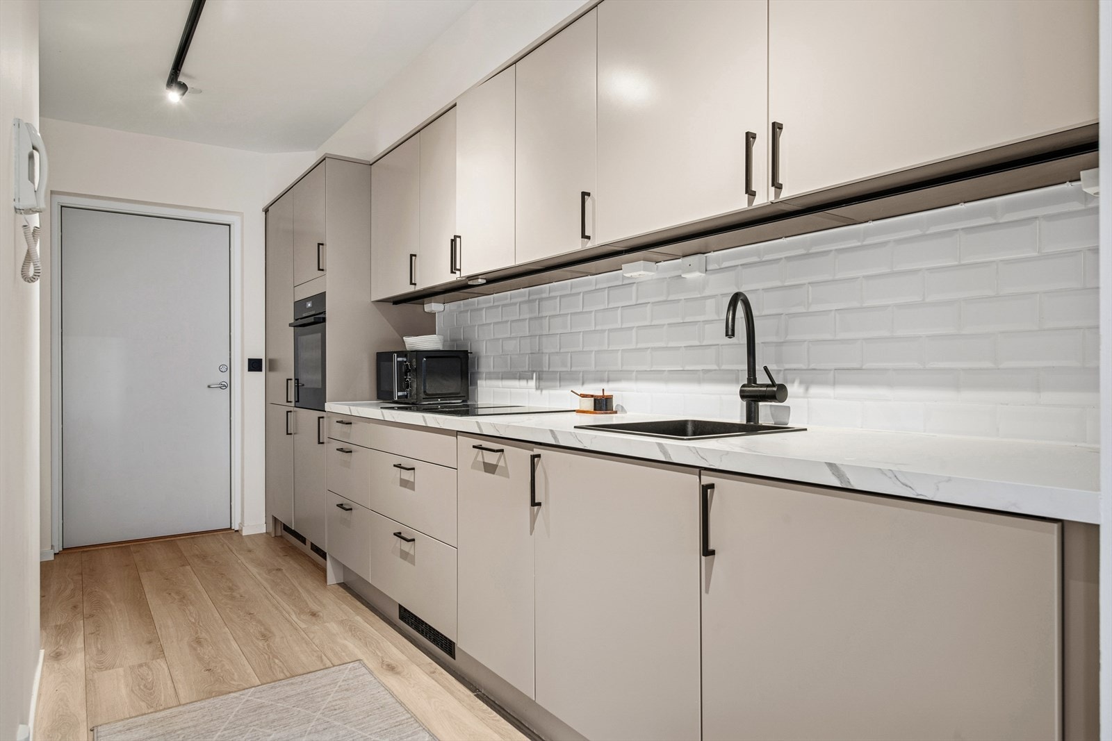 Høyskap i enden av kjøkkenet med integrert komfyr og kjøleskap. Galleribilde