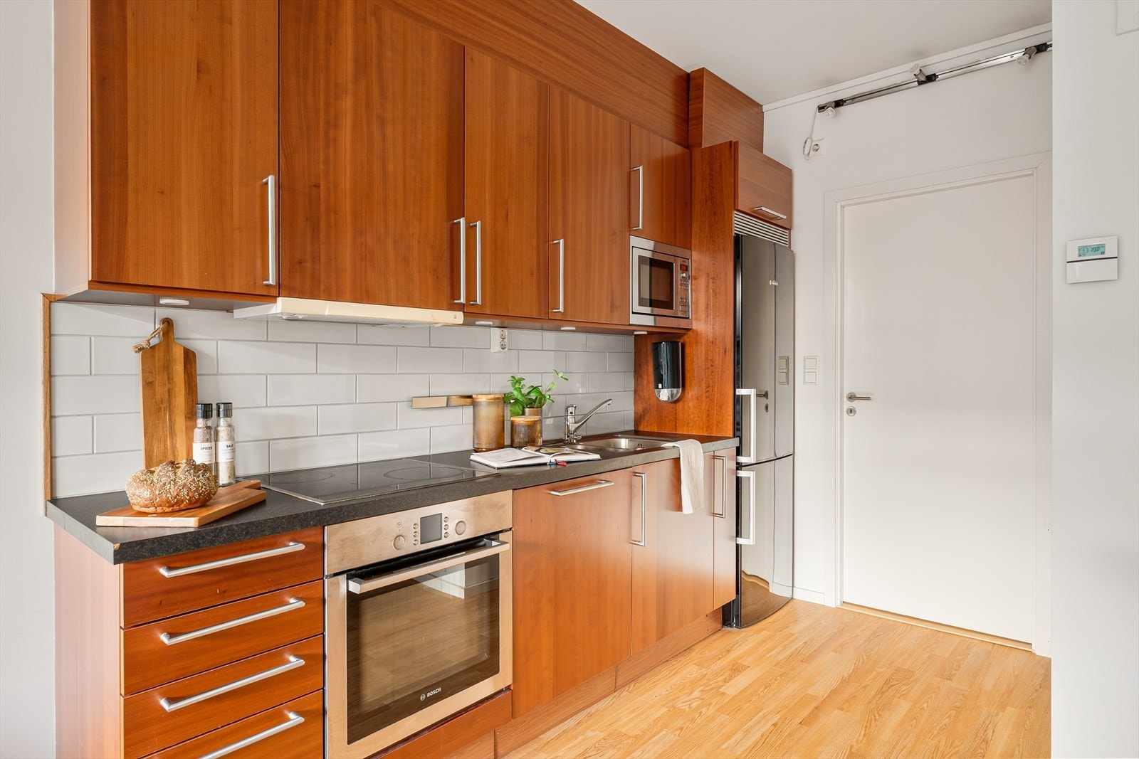 Funksjonelt kjøkken med slette fronter og benkeplate i laminat. Fliser mellom benk og overskap gir et tidløst og ryddig uttrykk. Galleribilde