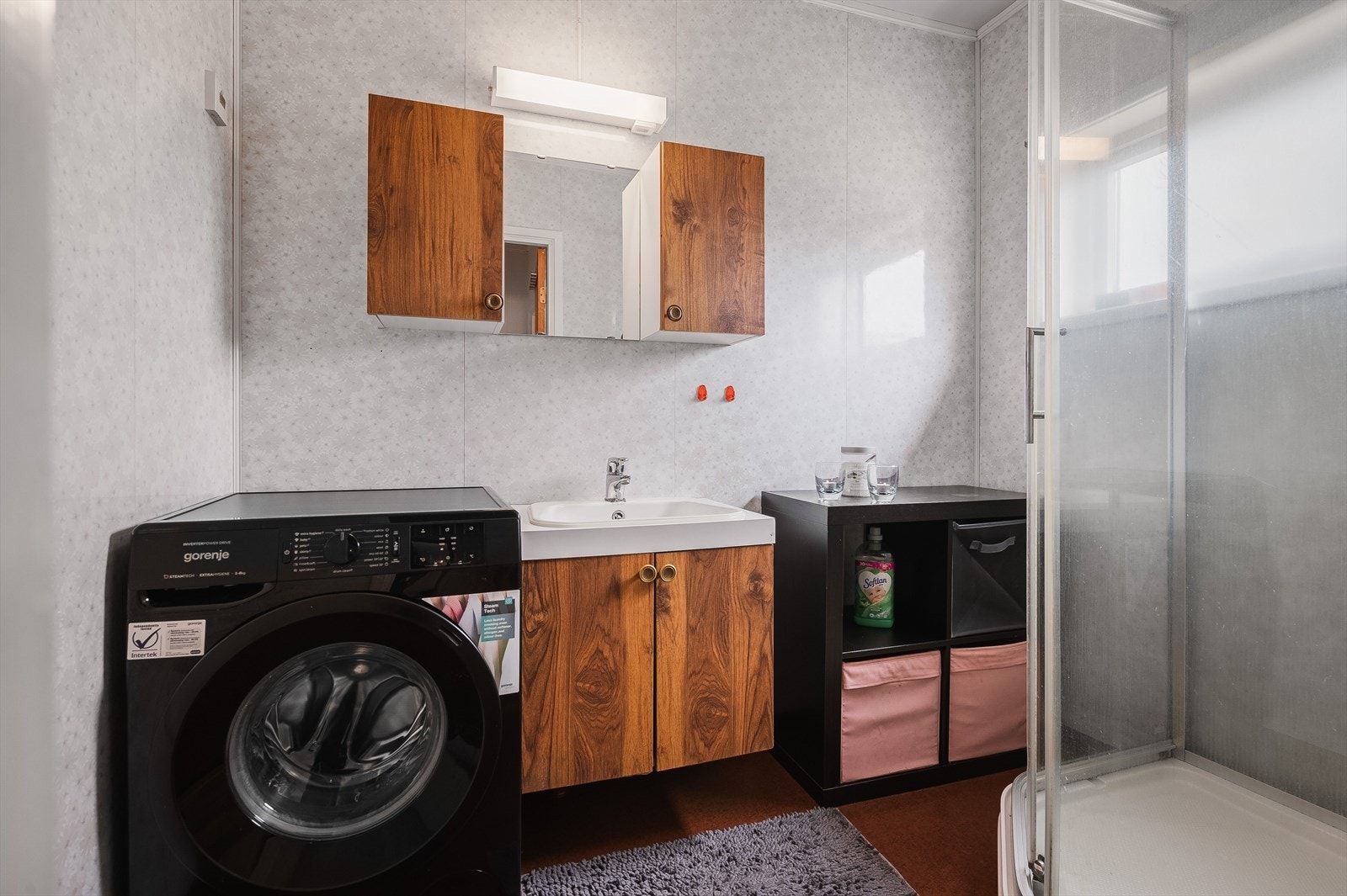 Bad med servant nedfelt i innredning, overskap, belyst speil, dusjkabinett og opplegg for vaskemaskin. Vegg-i-vegg med badet er det et separat toalettrom. Galleribilde