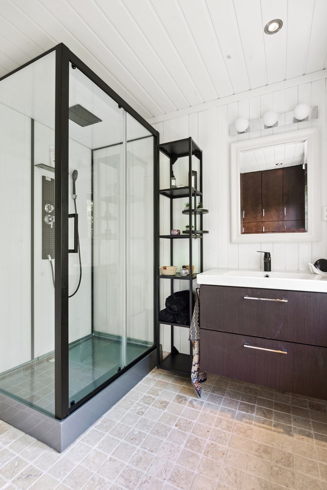 Badet er utstyrt med en baderomsinnredning med heldekkende servant og et dusjkabinett med integrert armatur. Galleribilde