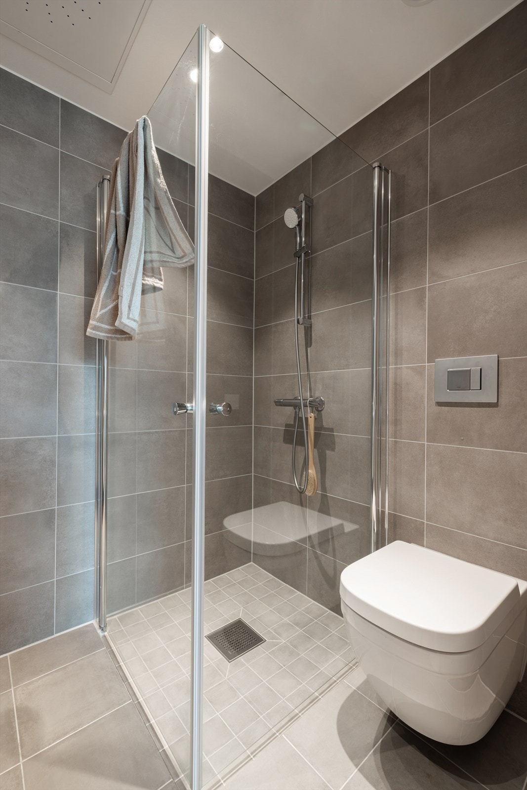 Badet har også vegghengt toalett, dusjhjørne med innfellbare glassdører, samt opplegg for vaskemaskin og tørketrommel i søyle, som gir både funksjonalitet og et ryddig uttrykk. Galleribilde