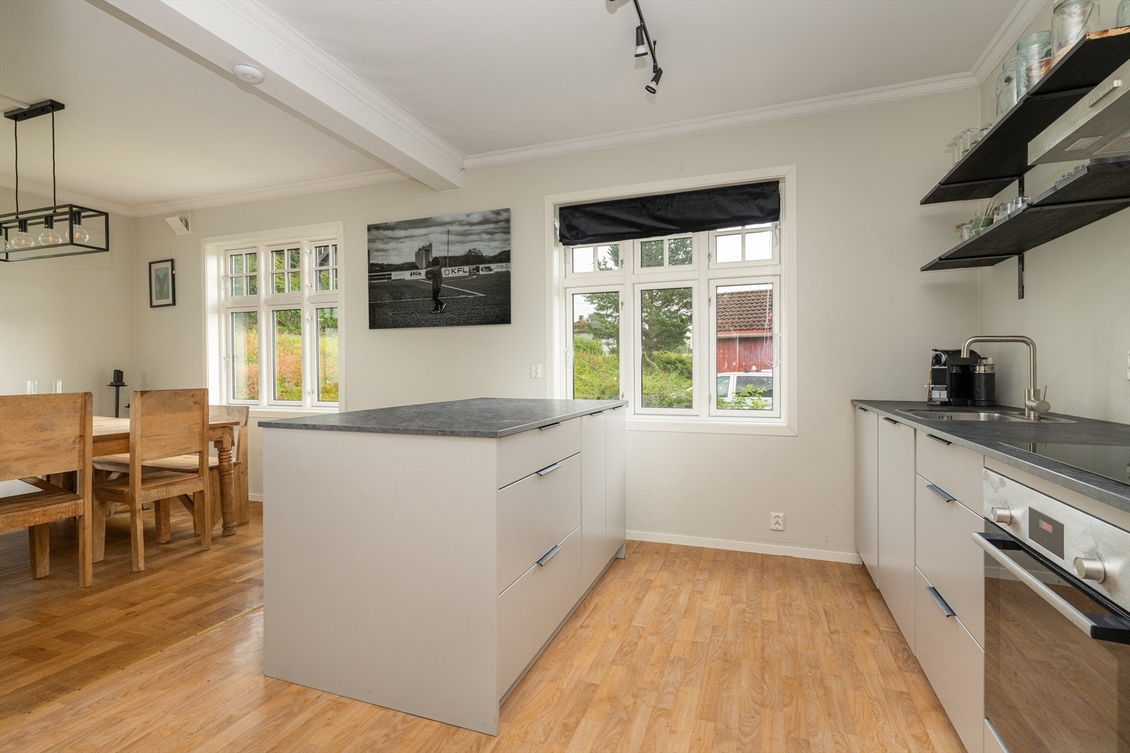 Pen laminat benkeplate med gode arbeidsflater. Nedfelt vask med blandebatteri og nedfelt platetopp. Over platetopp er det en vegghengt ventilator i stål med avtrekk ut. Galleribilde