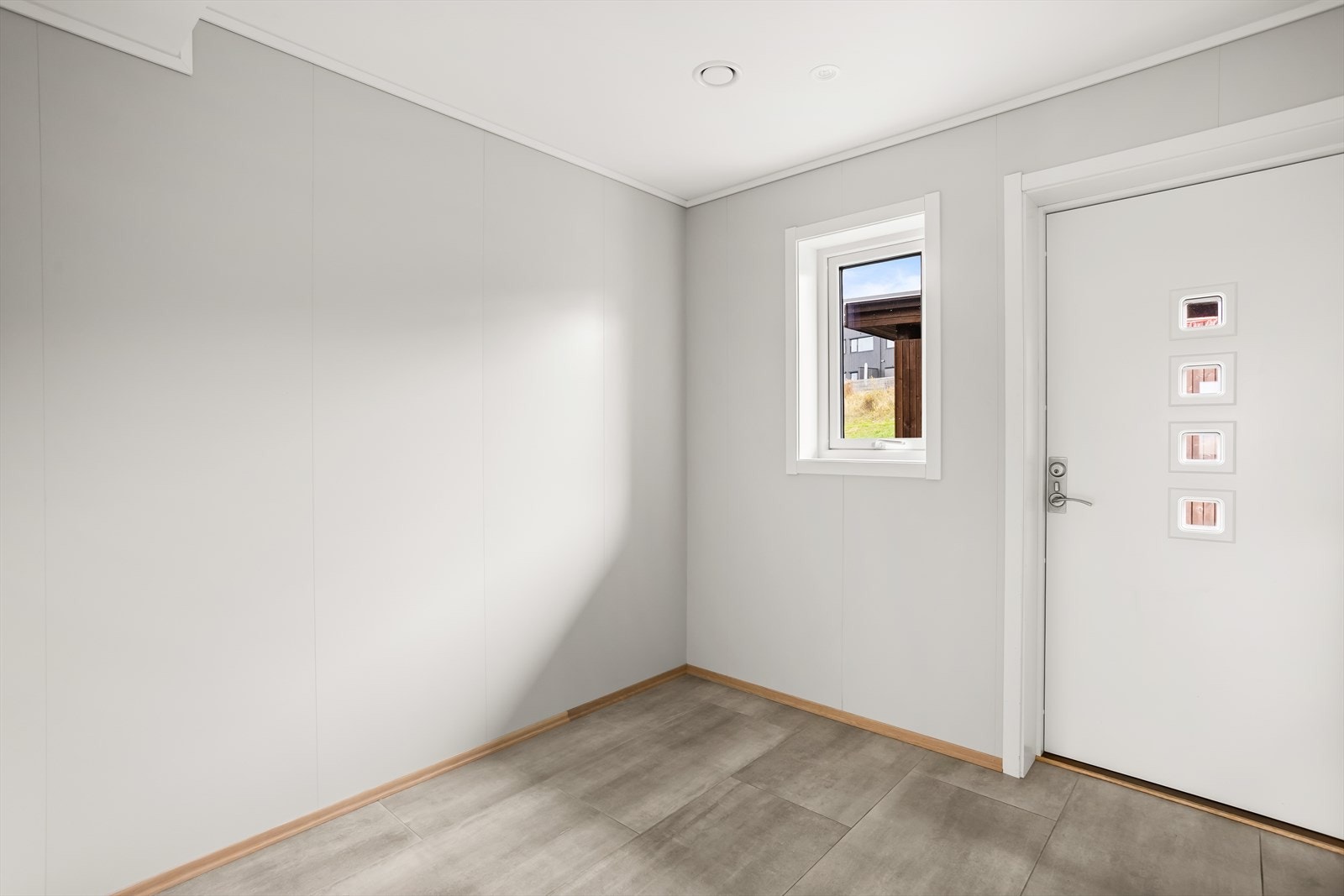 Fra et overbygget inngangsparti kommer man inn i en lys entré med flislagt gulv. Rommet har plass til garderobeløsning. Galleribilde