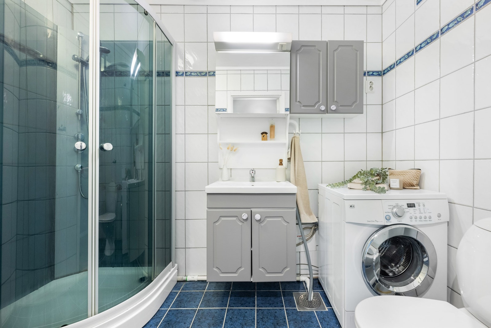Helfliset baderom med dusjkabinett og opplegg for vaskemaskin. Galleribilde