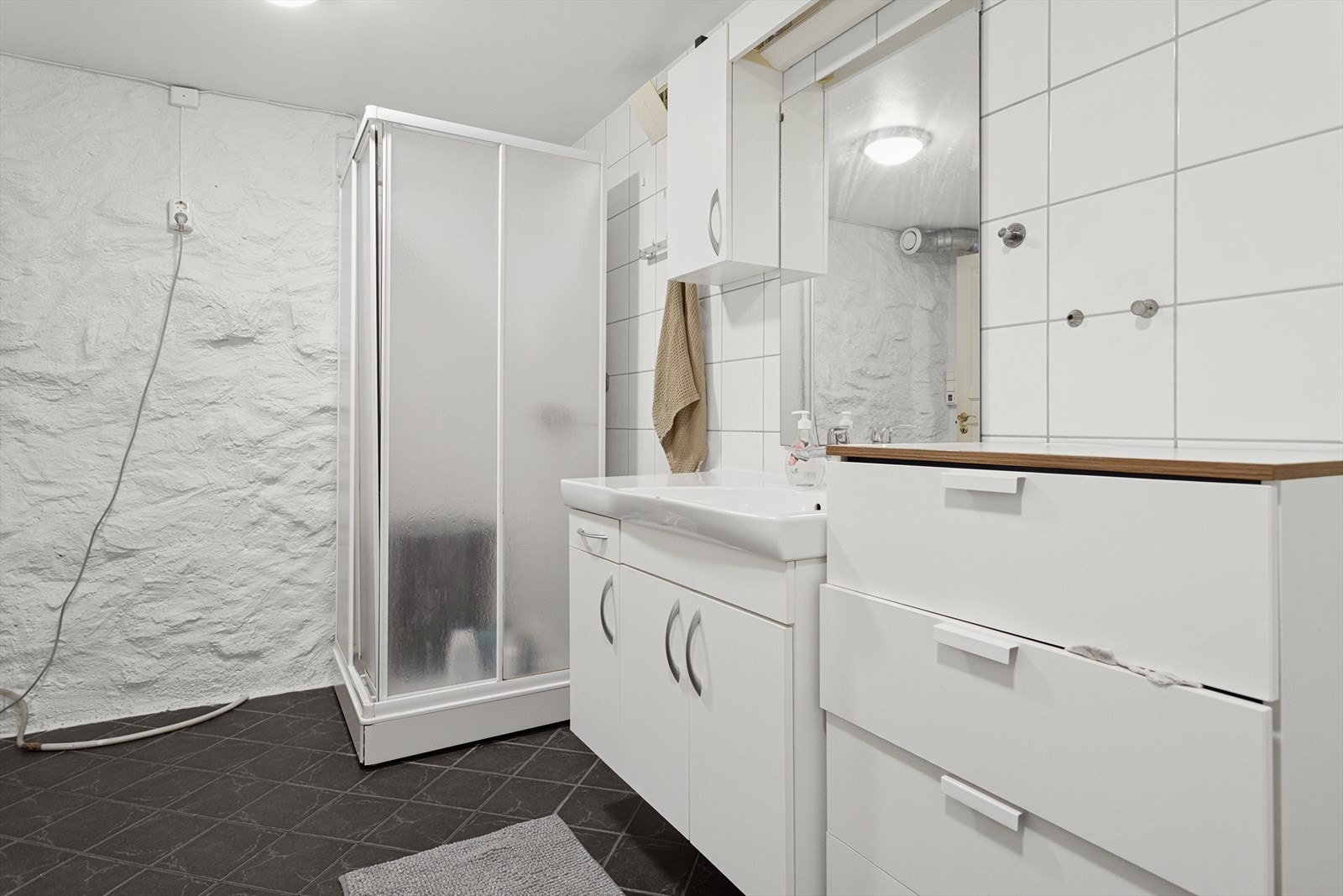 Dusjkabinett sørger for effektiv vannstyring på det flislagte badet. Galleribilde